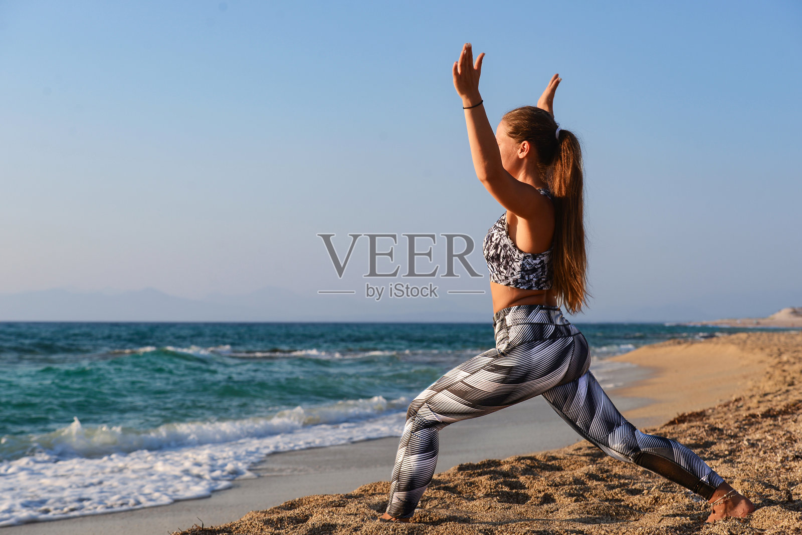 在海边的沙滩上练习瑜伽的女人照片摄影图片