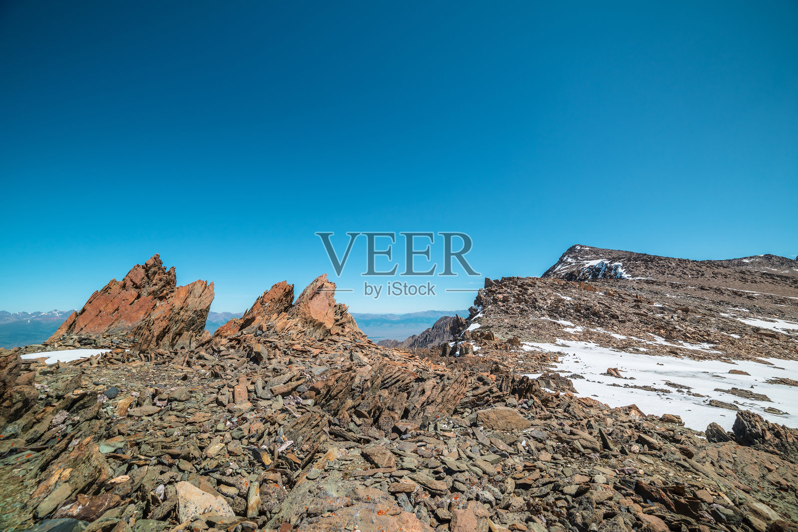 风景优美的山峦景观，阳光下的雪中有古老的岩石和石头。在阳光明媚的日子里，在蓝天下的高山上，有令人敬畏的高山风景。在非常高的海拔有锋利的岩石。照片摄影图片