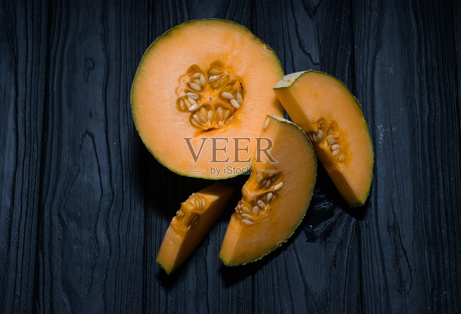 甜瓜上黑黑的底色，小巧可口漂亮的甜瓜，既有整块的，也有碎块的，折起来吃照片摄影图片