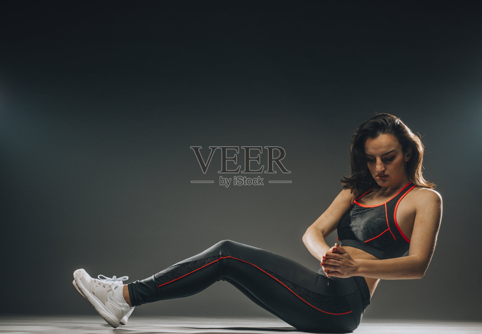 柔韧美丽的体操女孩做体操练习，做伸展腿，在一个黑暗的背景照片摄影图片