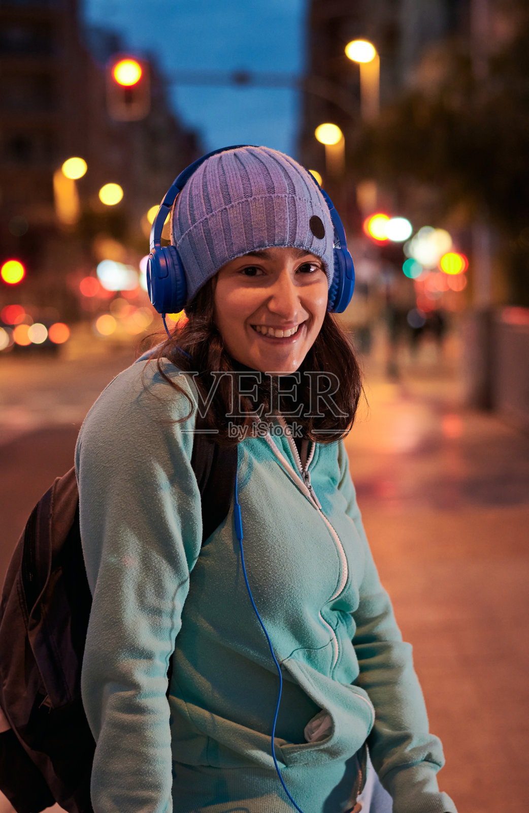 一名年轻女子微笑的肖像，看着相机与城市的灯光在晚上照片摄影图片