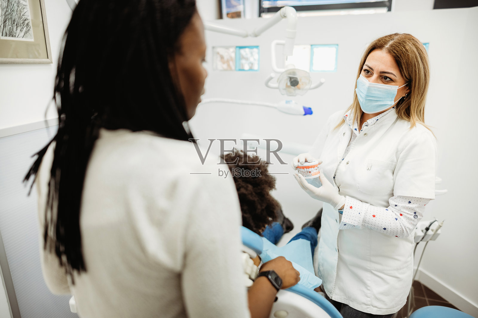 小女孩坐在牙医的椅子上。照片摄影图片