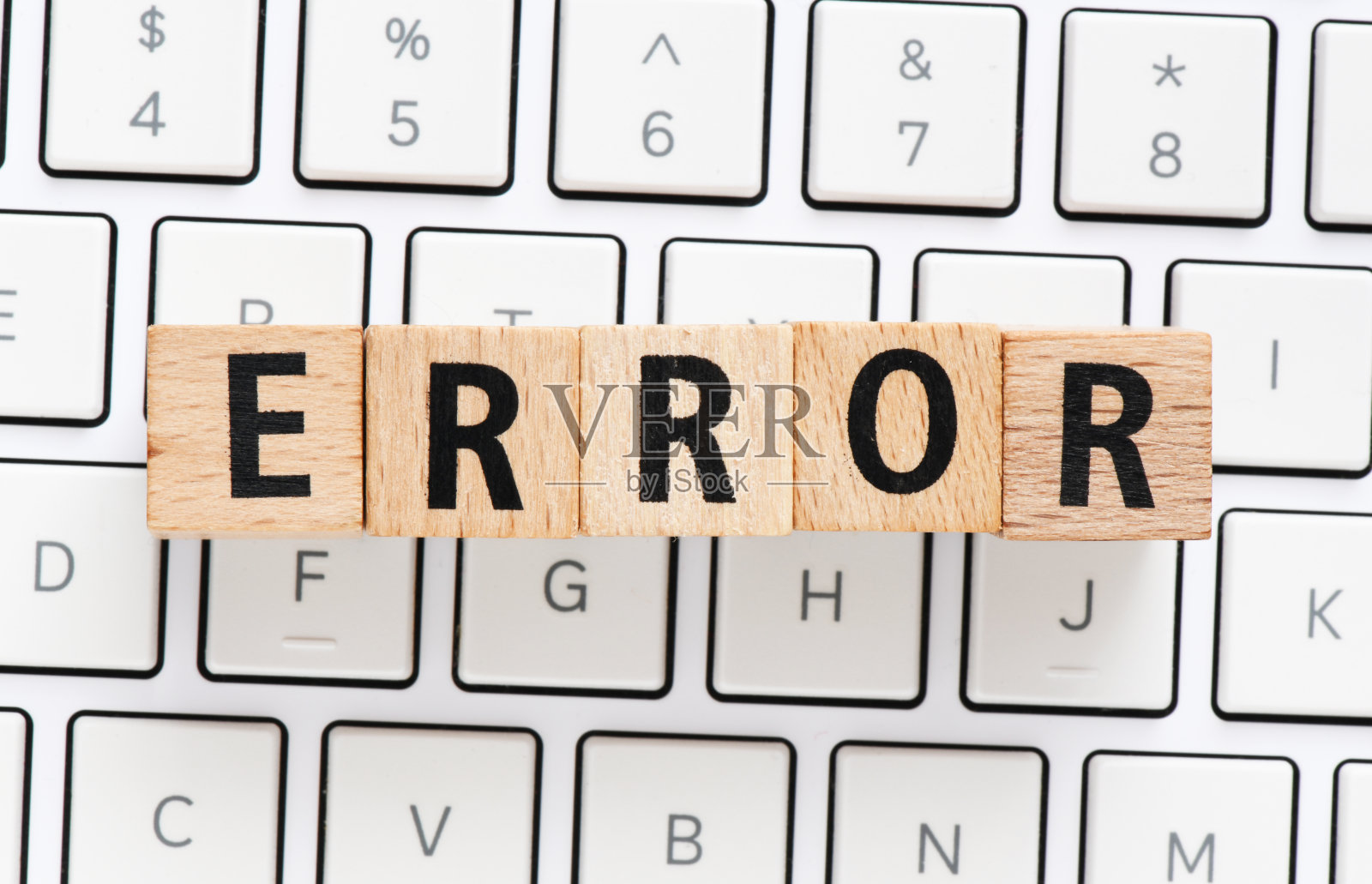 键盘上出现木制字母组成的错误单词。照片摄影图片