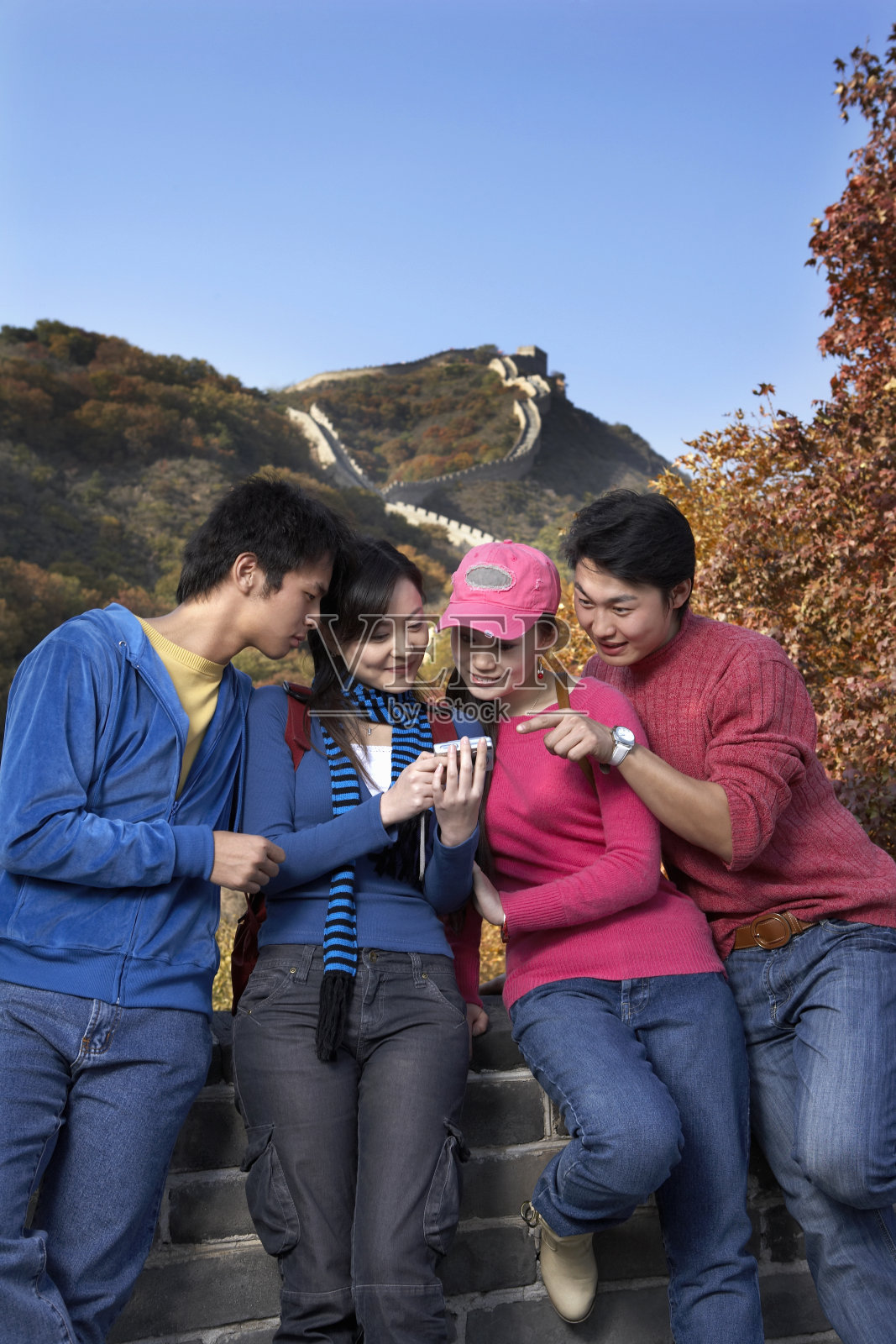四个年轻人正在欣赏他们在长城上的留影照片摄影图片