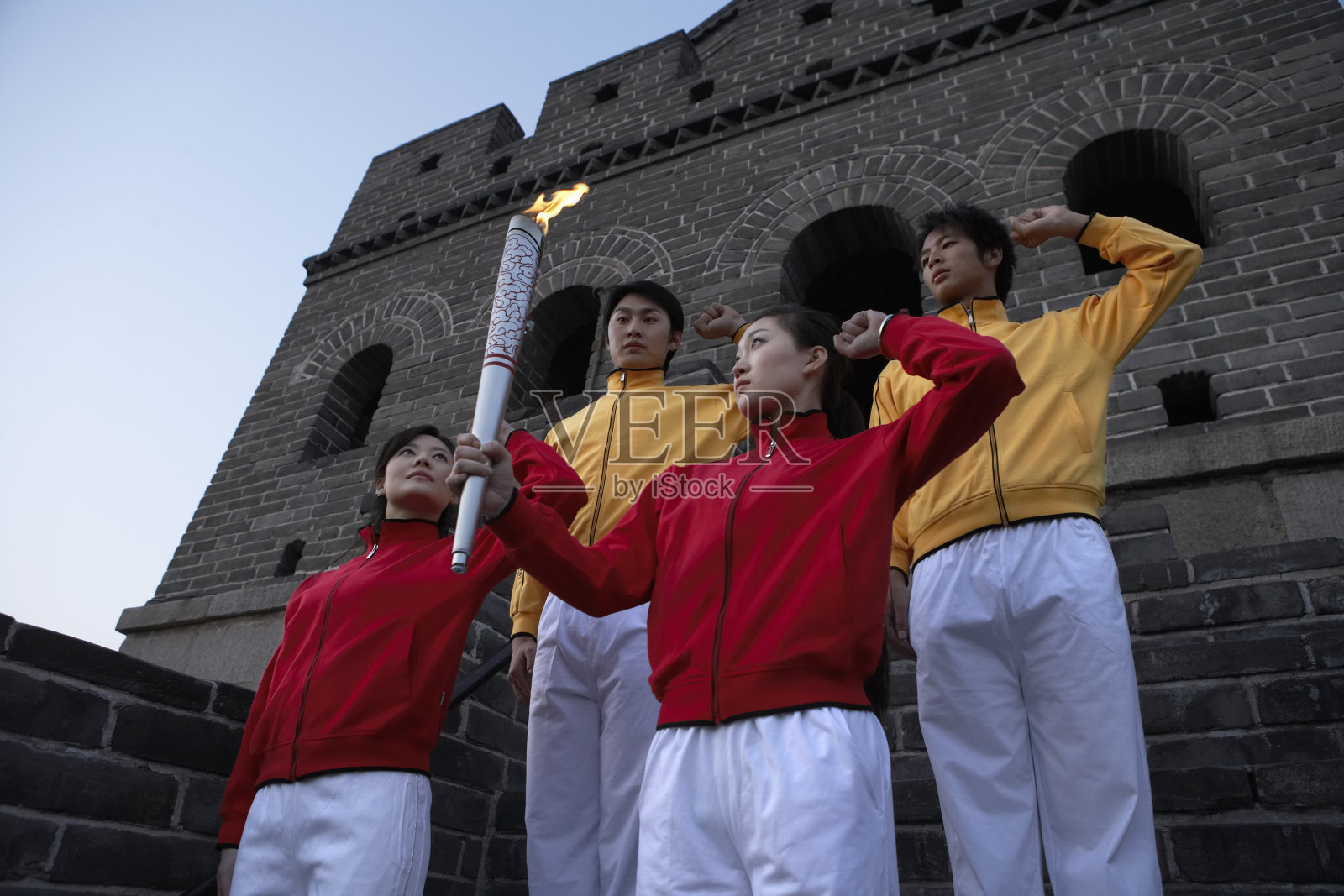 四位身穿运动服的年轻人在奥运火炬前宣誓照片摄影图片