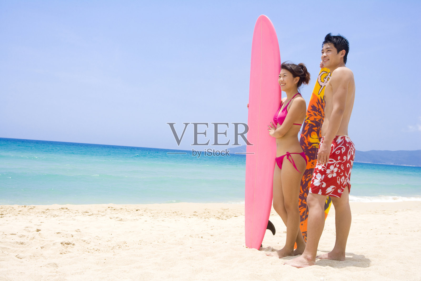 拿着冲浪板站在沙滩上的人照片摄影图片