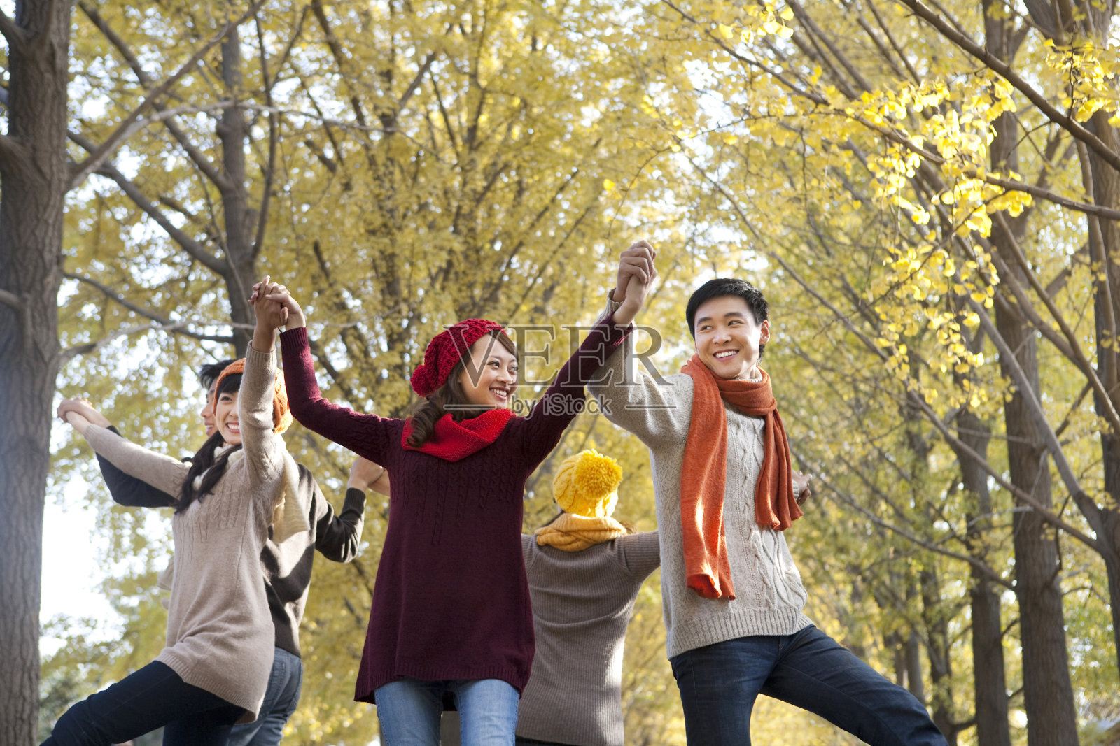 年轻人在秋日午后树林跳跃照片摄影图片