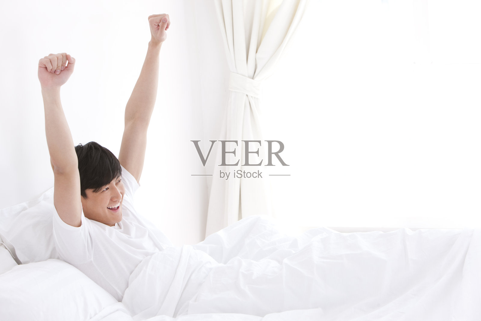 床上伸懒腰的年轻男士照片摄影图片