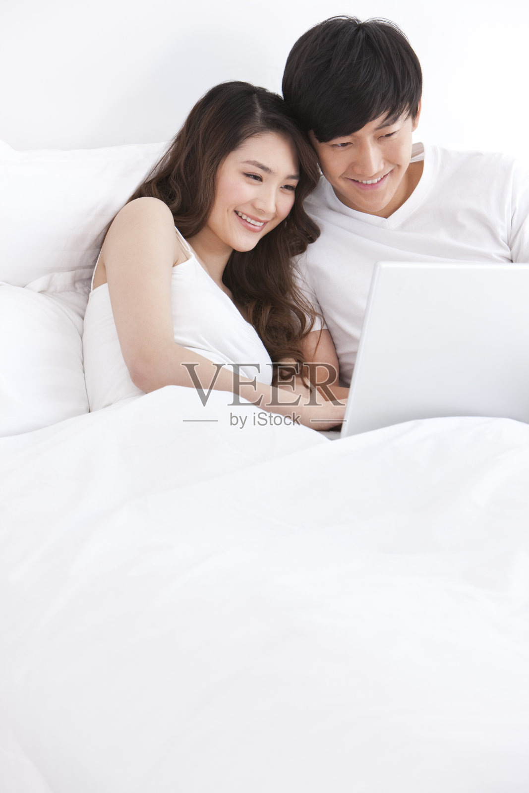 床上用笔记本电脑的年轻夫妇照片摄影图片