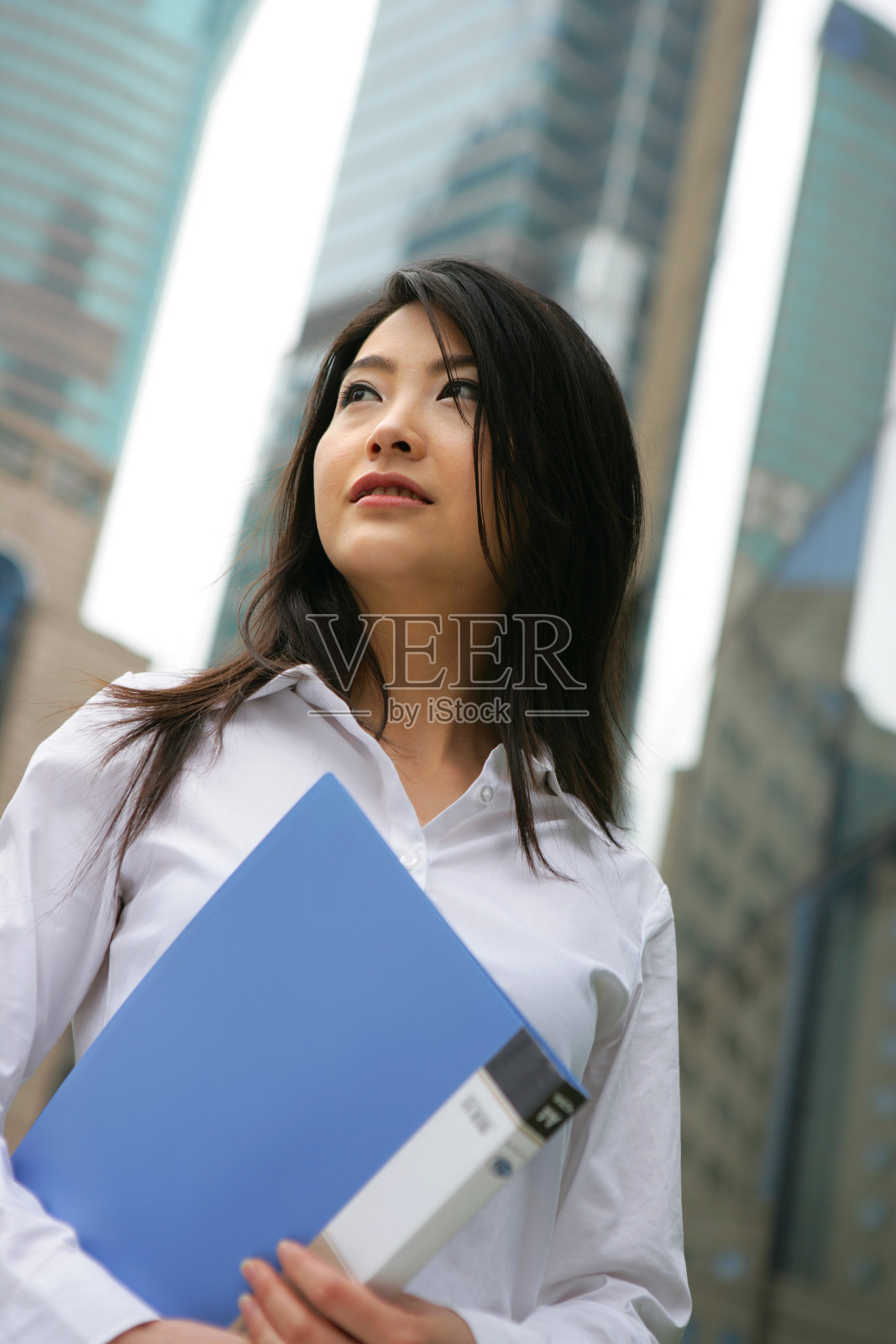 上海浦东写字楼旁一位女商务人士拿文件夹站立照片摄影图片