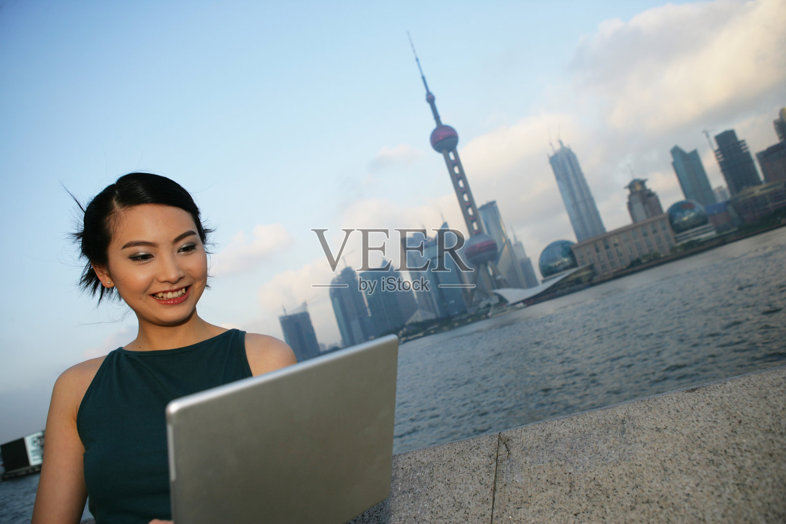 外滩黄浦江边一位女青年使用笔记本电脑照片摄影图片