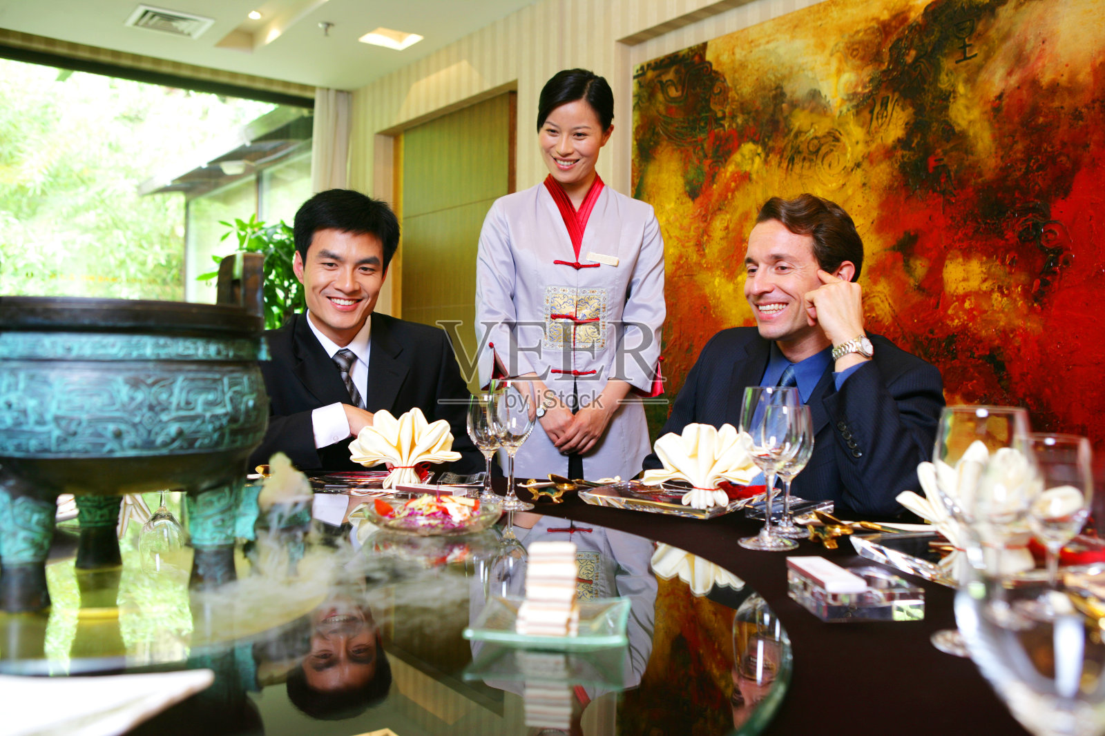 中外商务人士坐在酒店餐桌旁把玩工艺品照片摄影图片