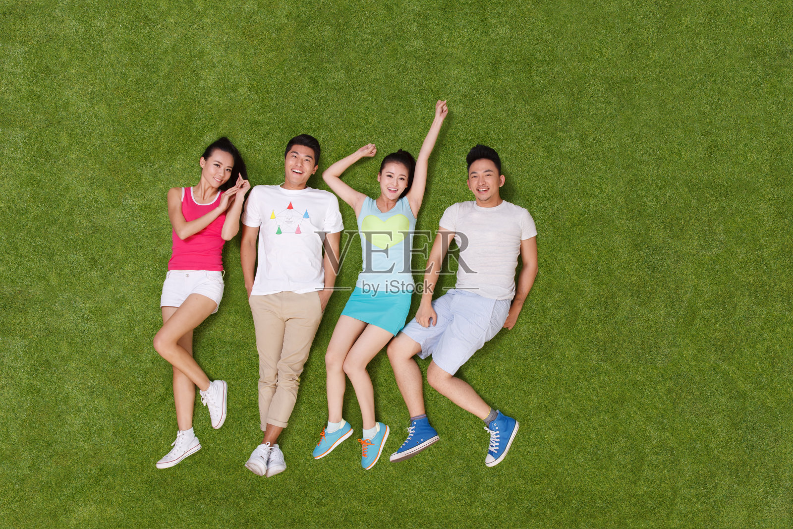 年轻男女躺在草地上嬉戏照片摄影图片