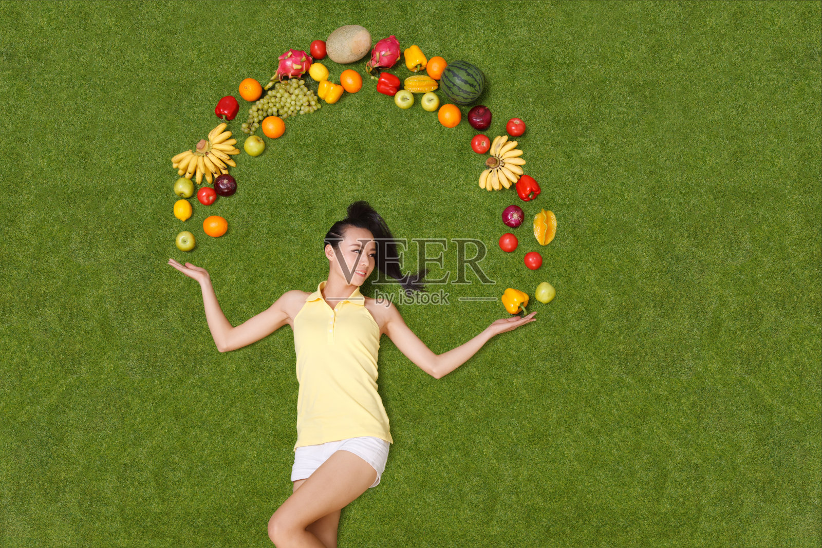 年轻女子手托着水果躺在草地上照片摄影图片