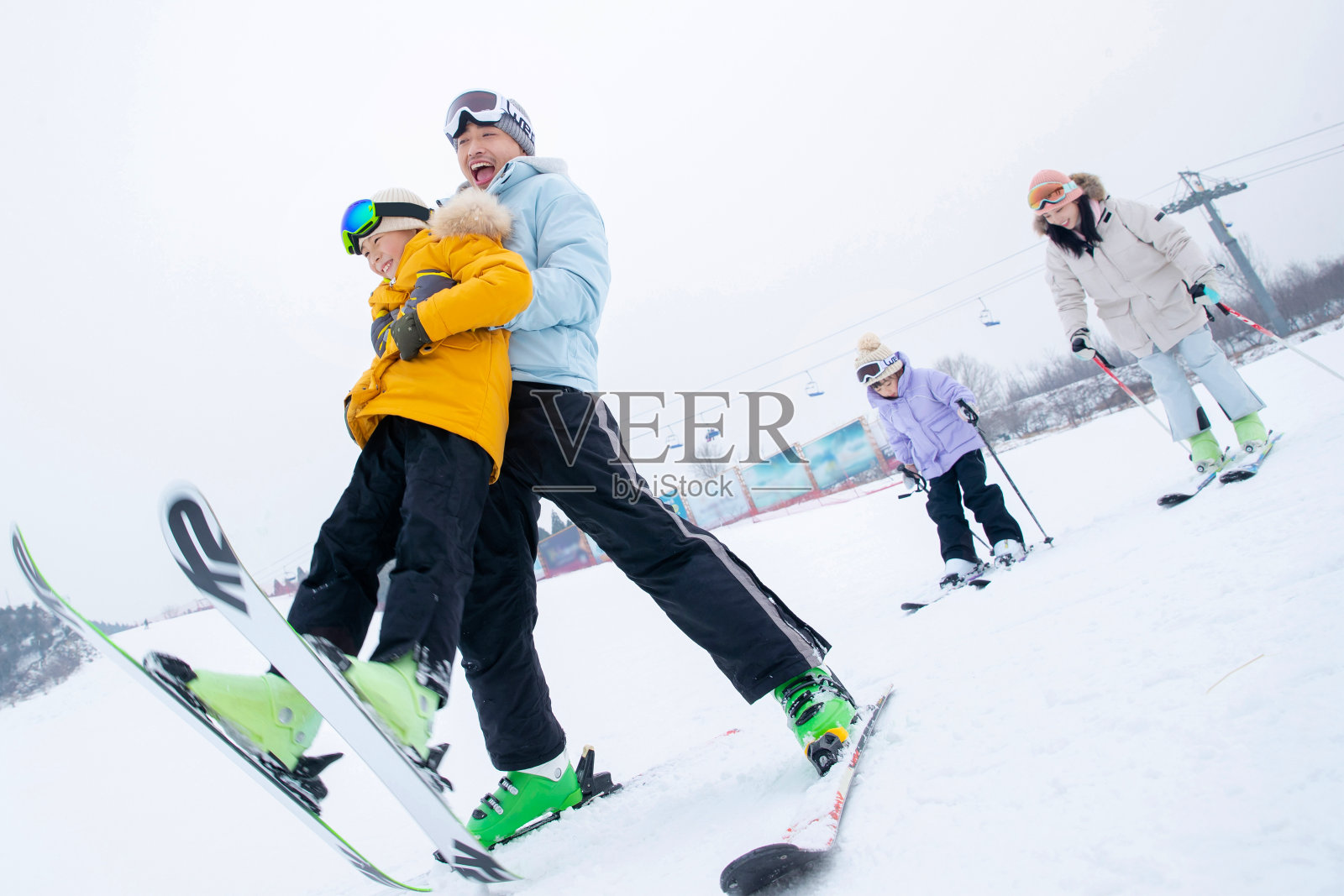 滑雪场内边滑雪边嬉戏的一家四口照片摄影图片