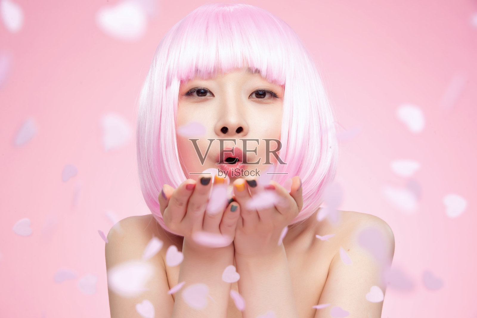 年轻女孩吹撒手中的心形纸片照片摄影图片