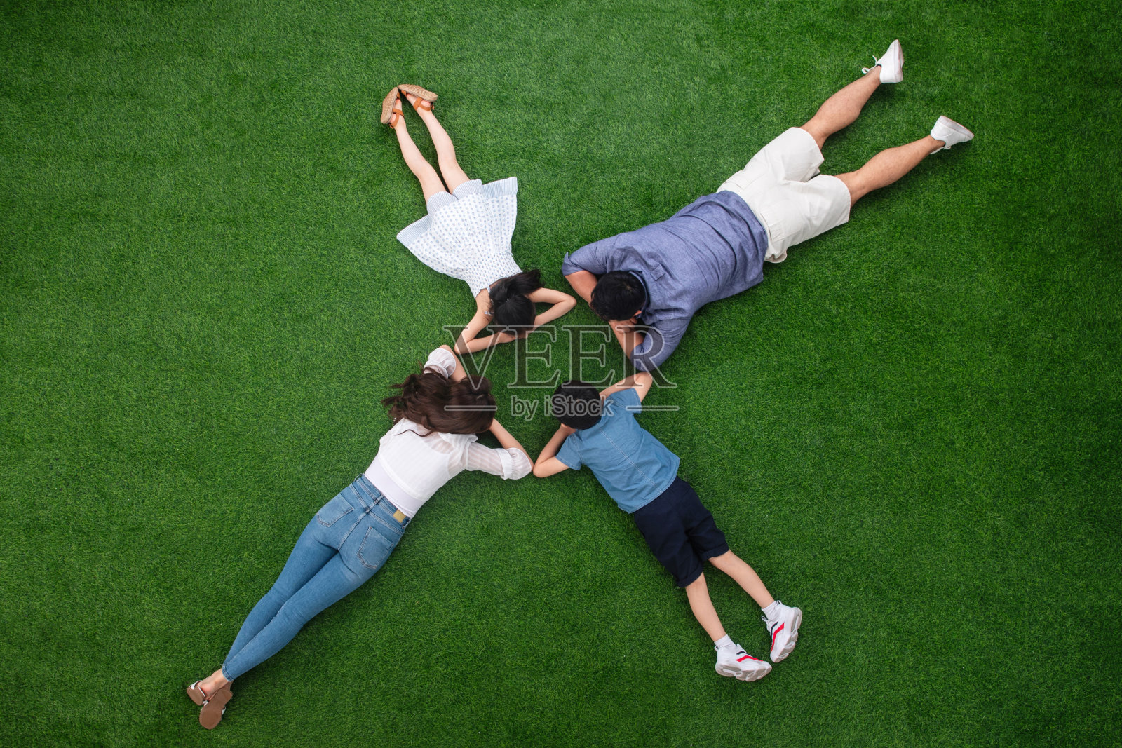 幸福的一家四口趴在草地上照片摄影图片