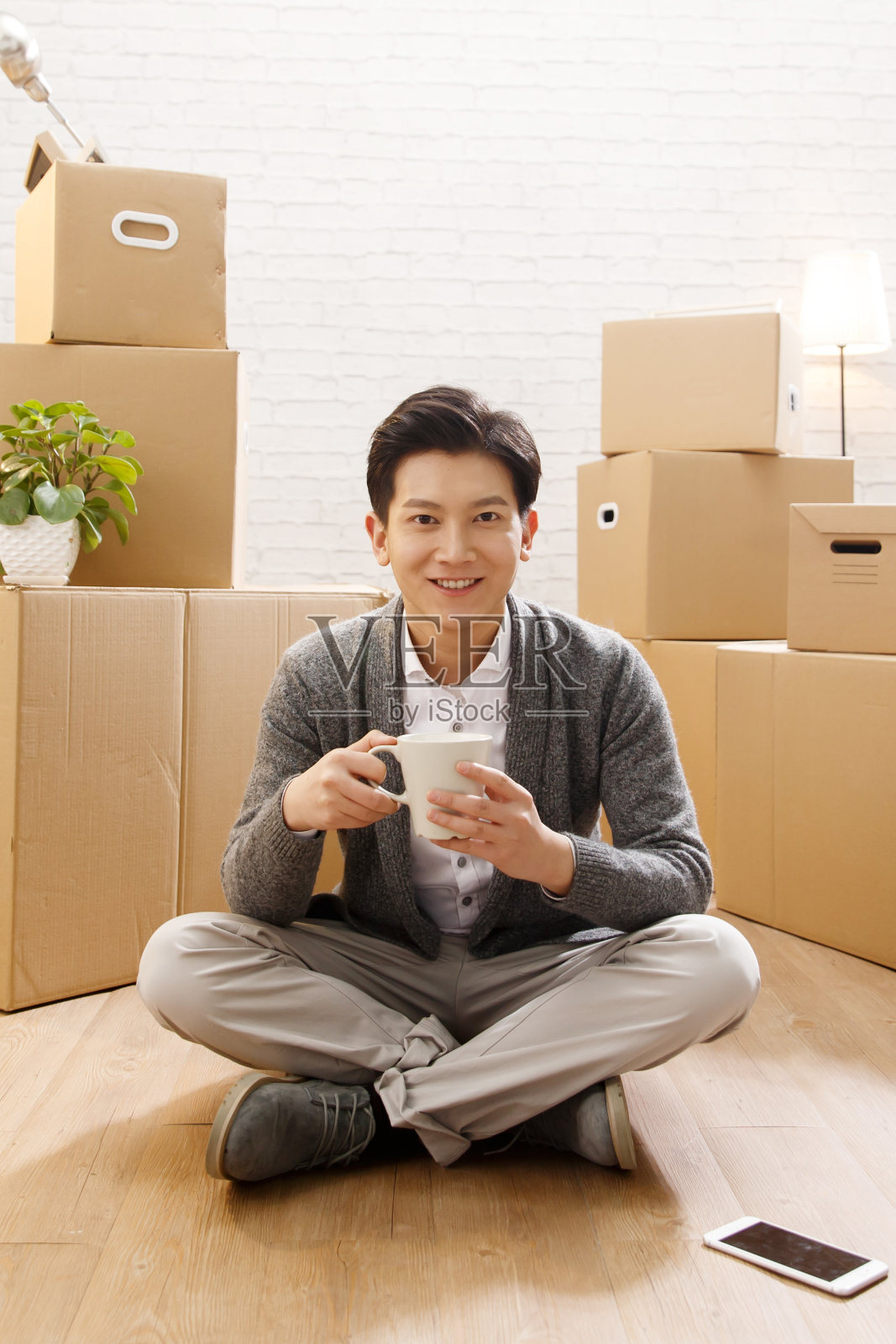 青年男人坐在地板上喝水照片摄影图片