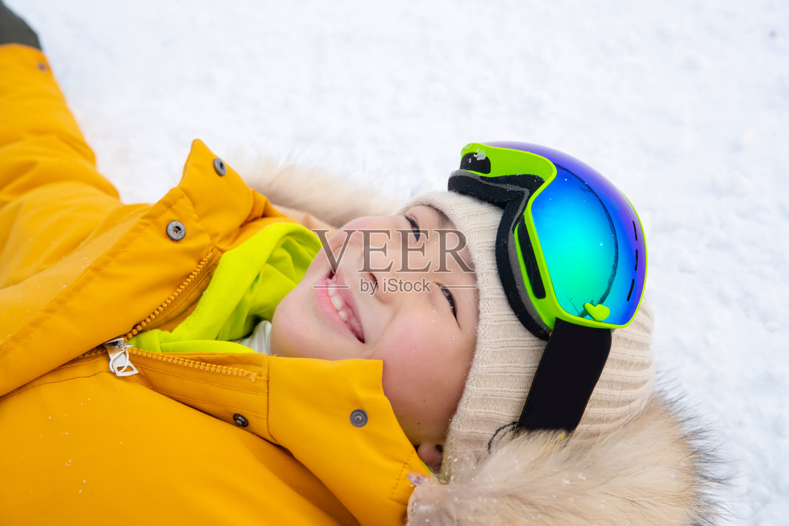 躺在雪地上的快乐男孩照片摄影图片