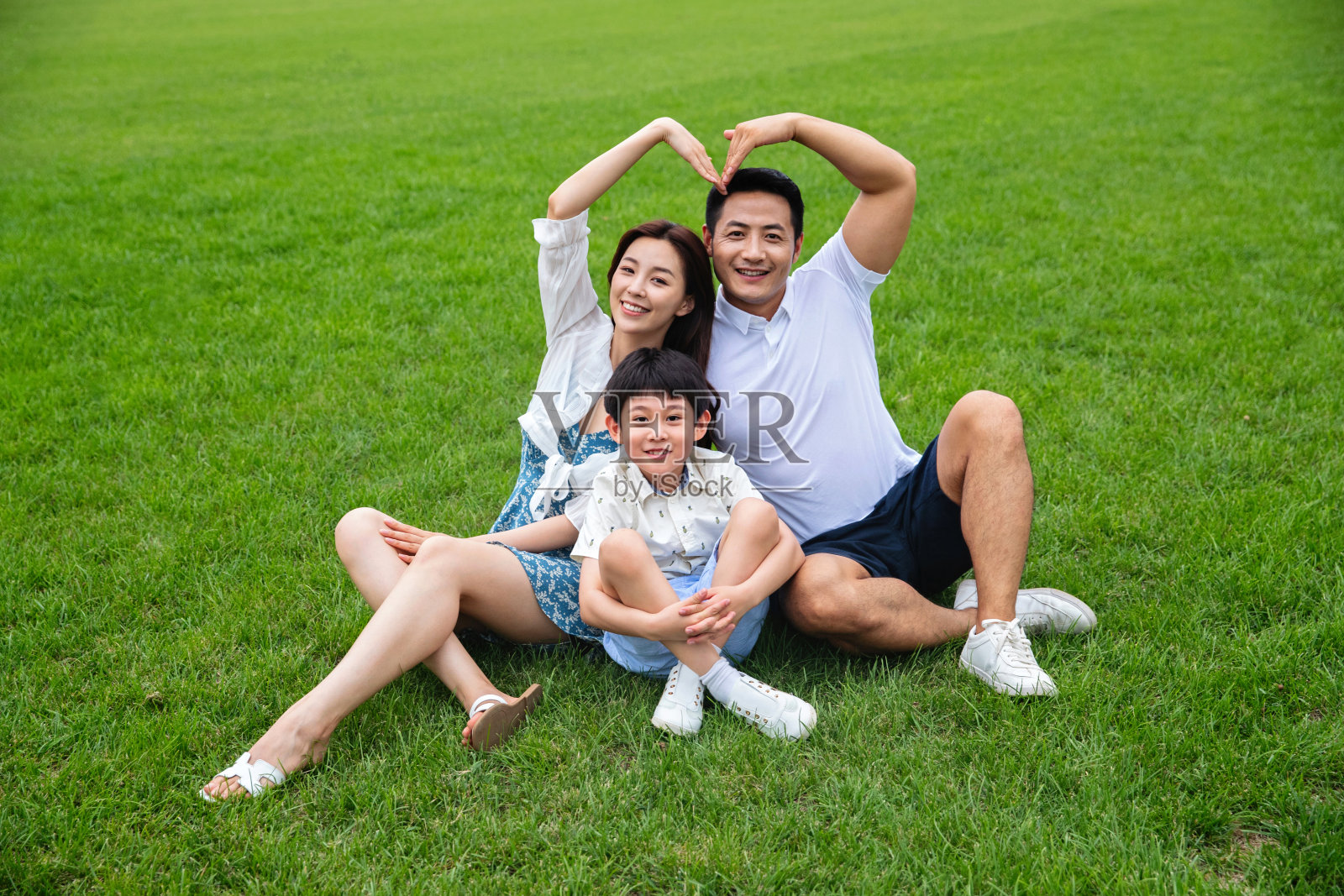 幸福的三口之家坐在草地上照片摄影图片