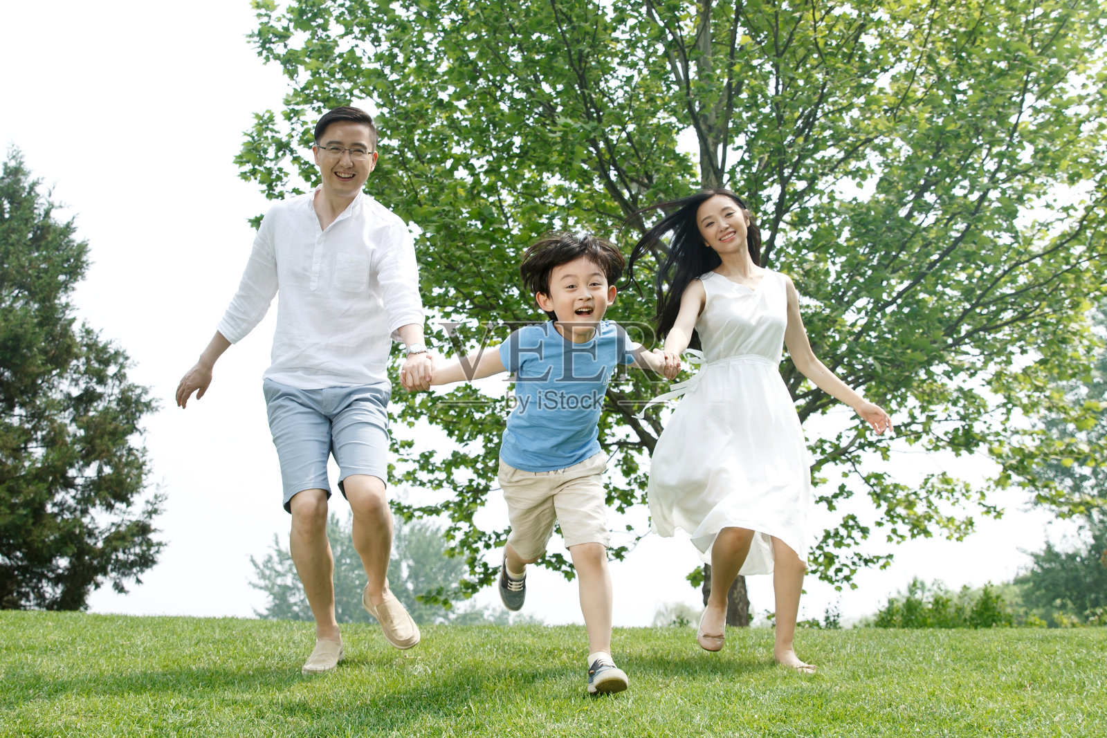 一家三口在草地上玩耍照片摄影图片