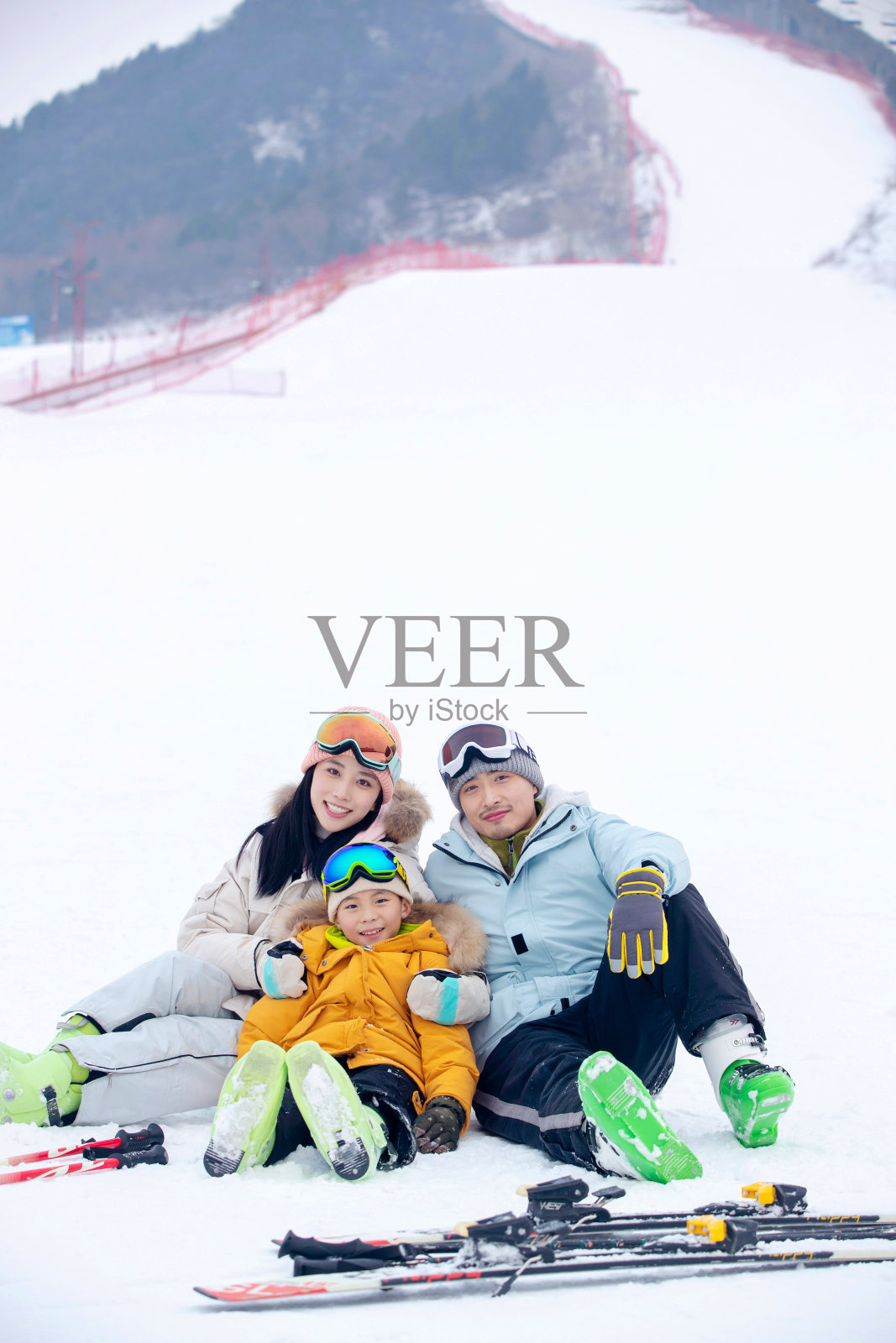 雪场上坐在雪道上的一家三口照片摄影图片