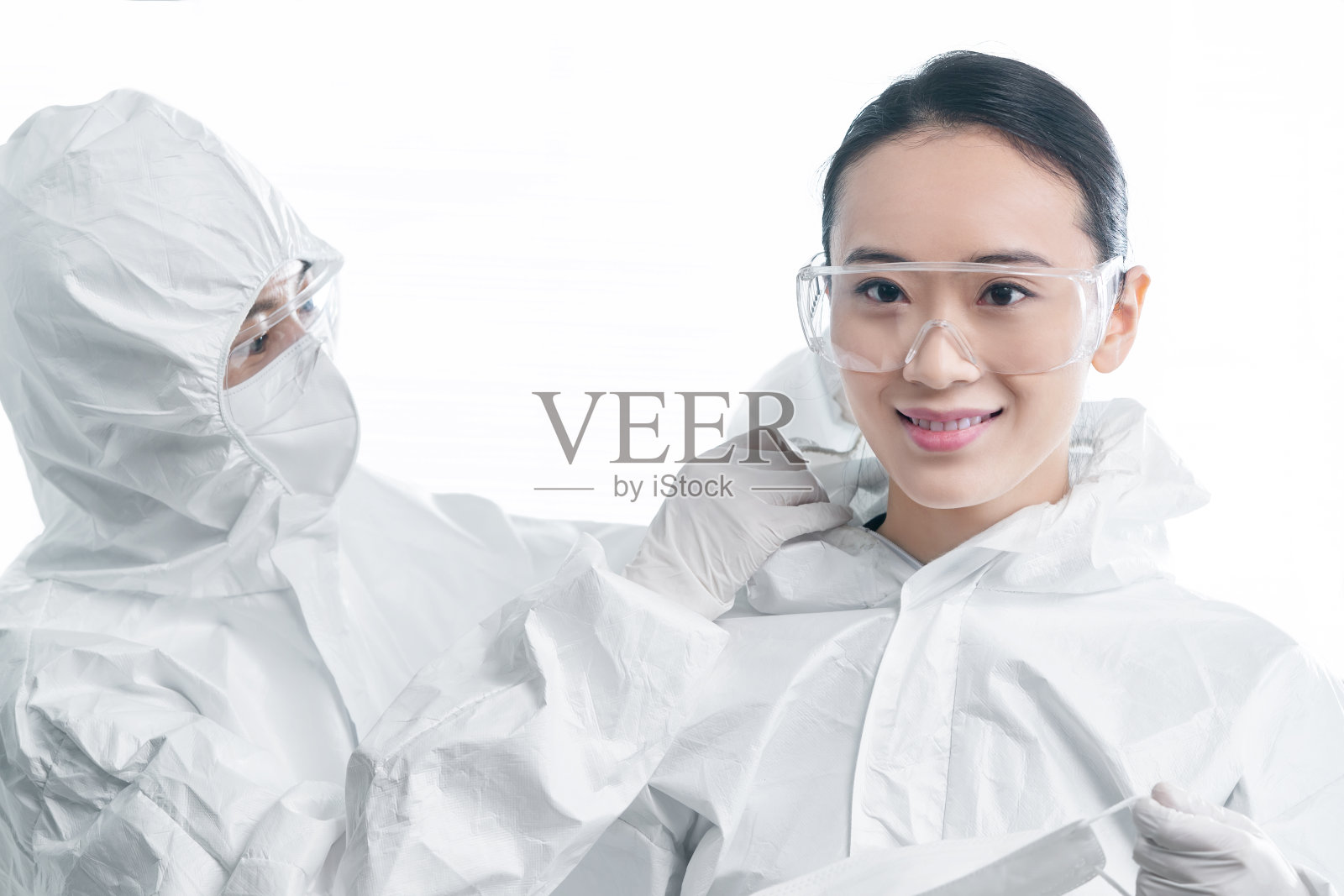 年轻女医生互相协助穿防护服照片摄影图片