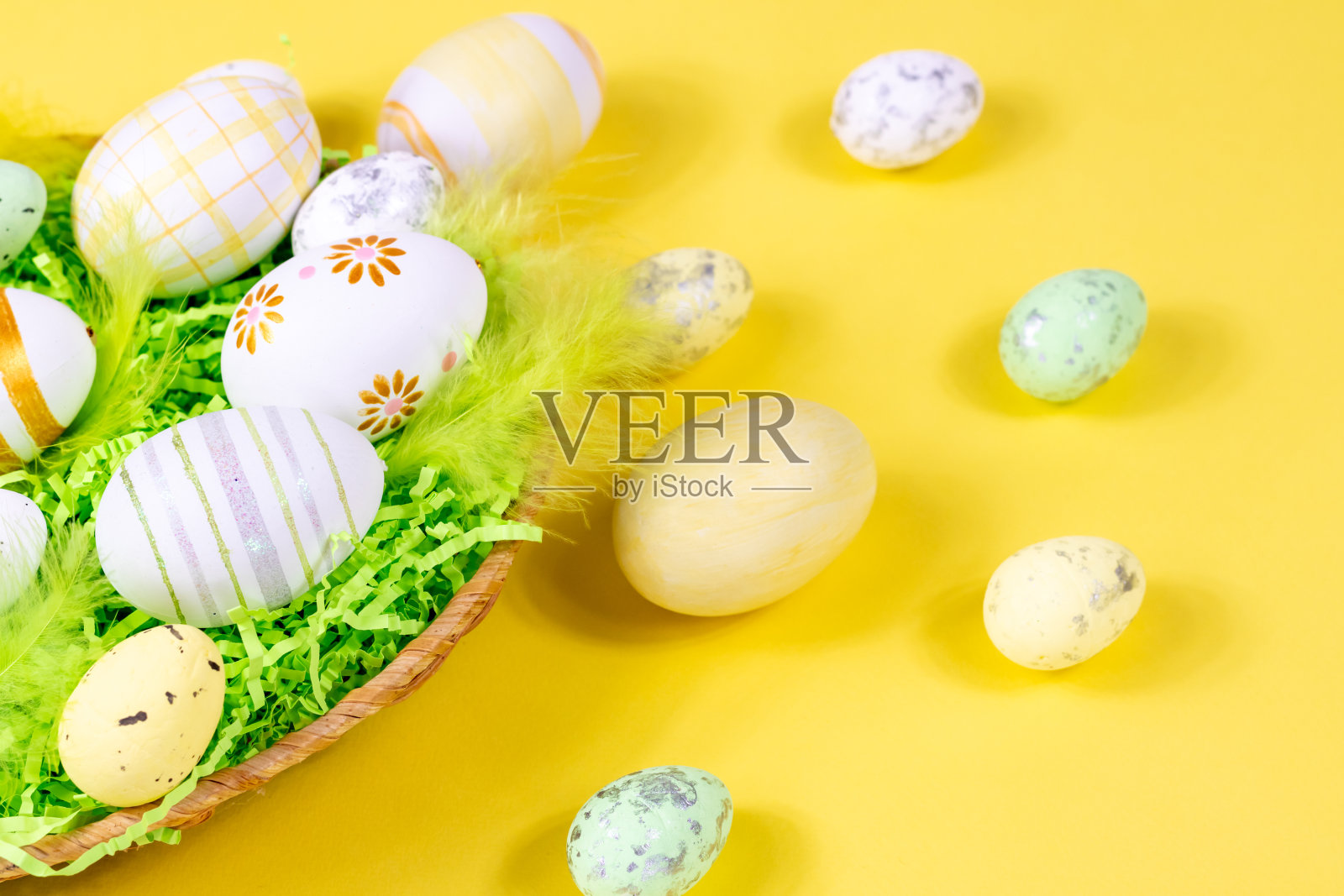 复活节鸟巢与蛋和羽毛在黄色背景的特写。最小的概念。照片摄影图片