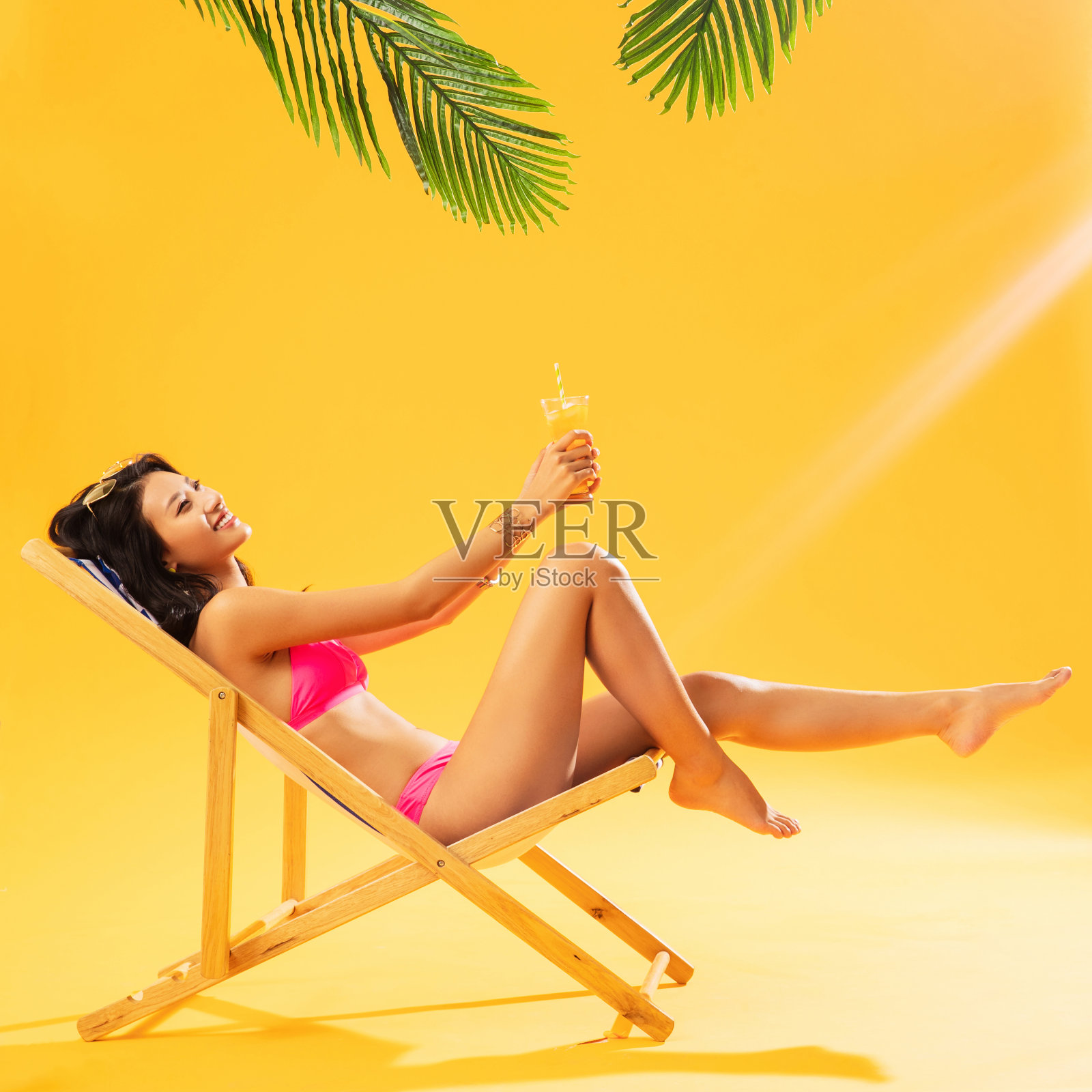 坐在躺椅上喝饮料的比基尼美女照片摄影图片