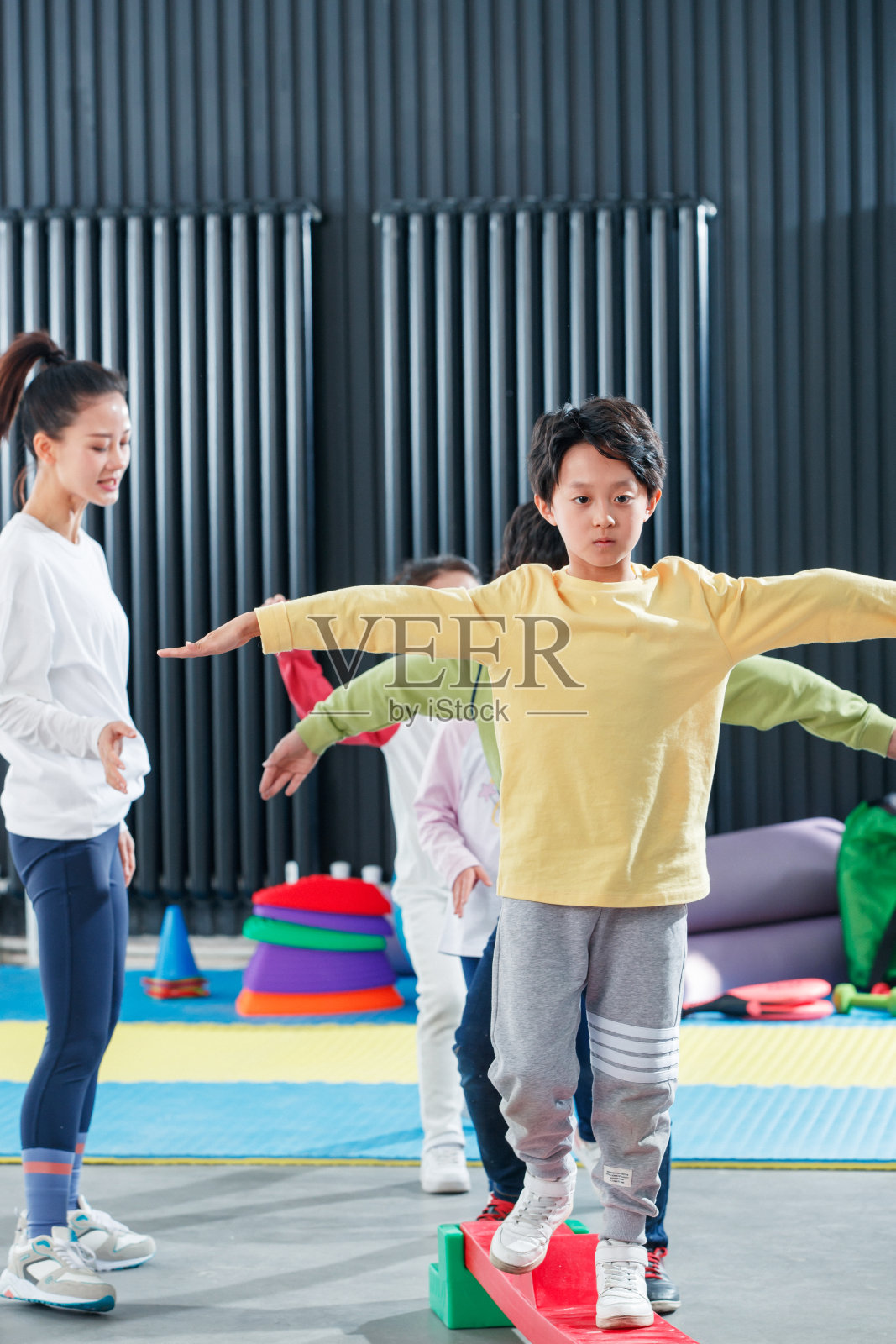 儿童在教练的指导下进行平衡木训练照片摄影图片