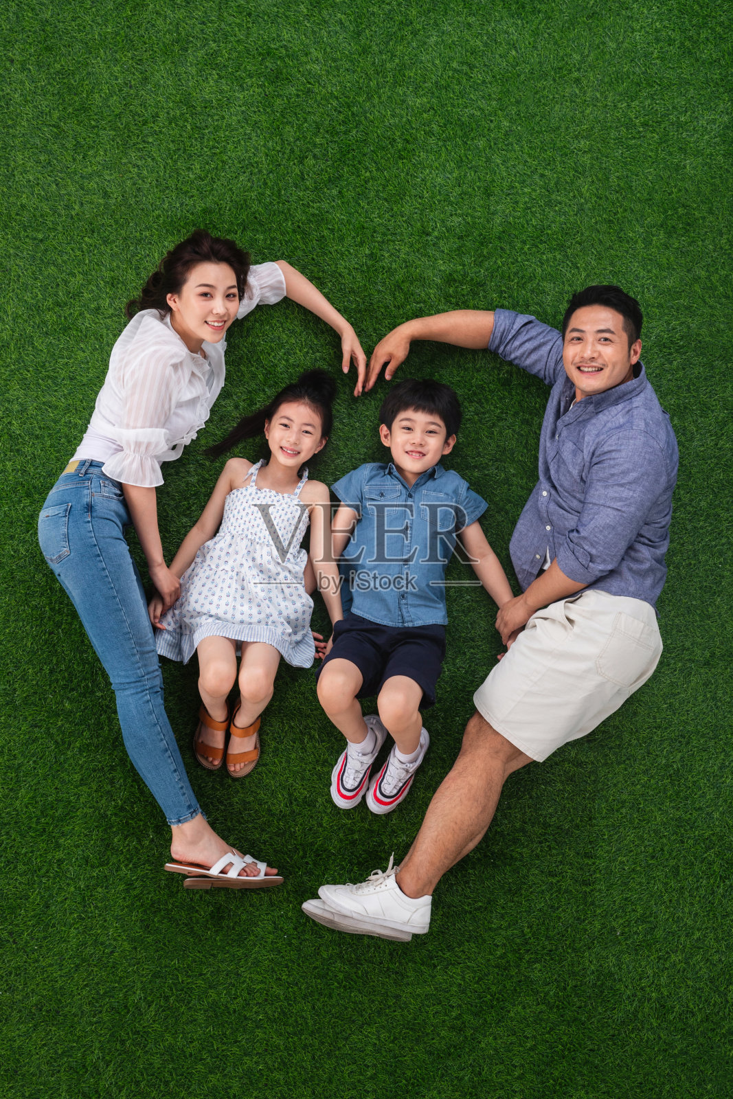 幸福的四口之家躺在草地上组成心形照片摄影图片