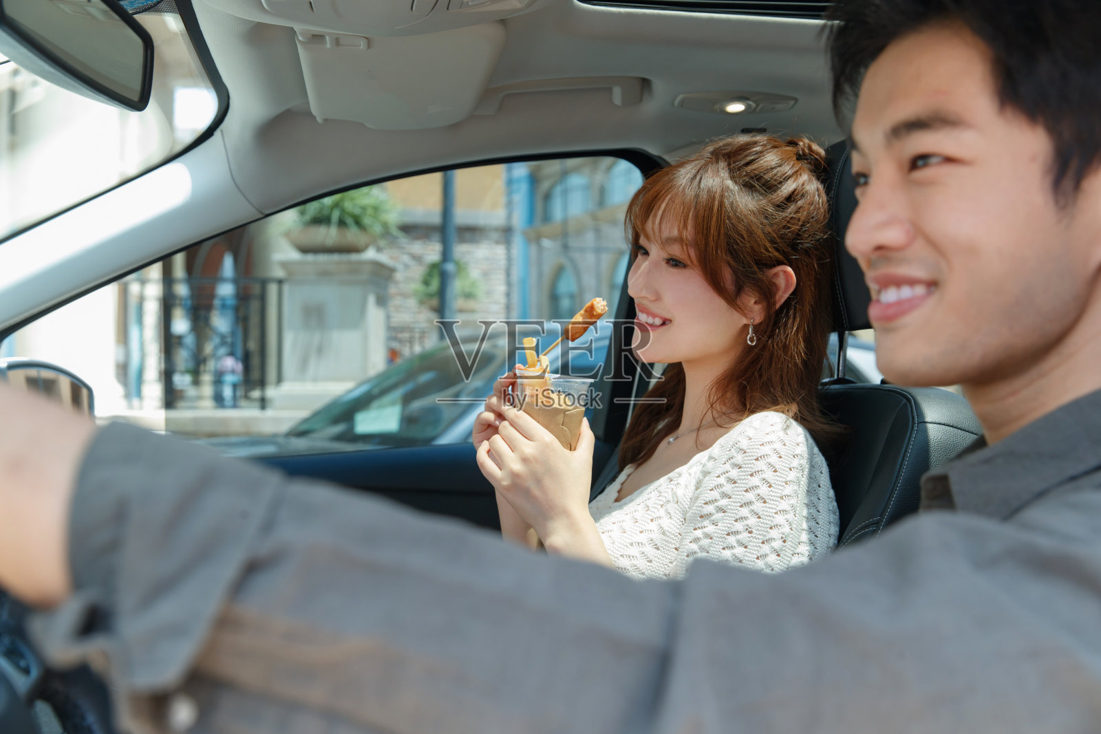 坐在汽车里的青年情侣吃东西照片摄影图片