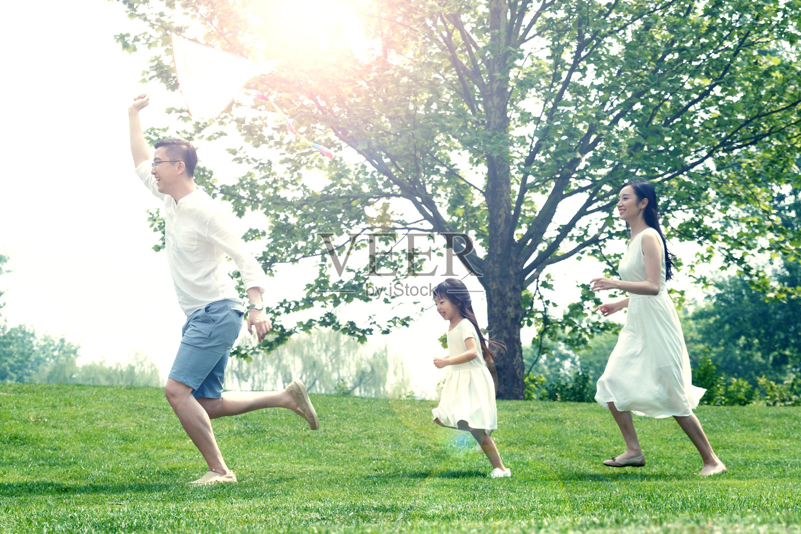 一家三口在草地上放风筝照片摄影图片