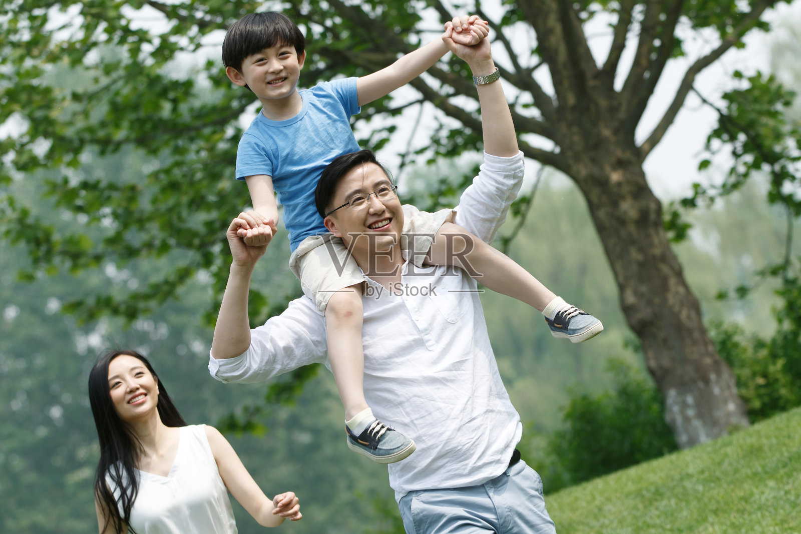 一家三口在草地上玩耍照片摄影图片