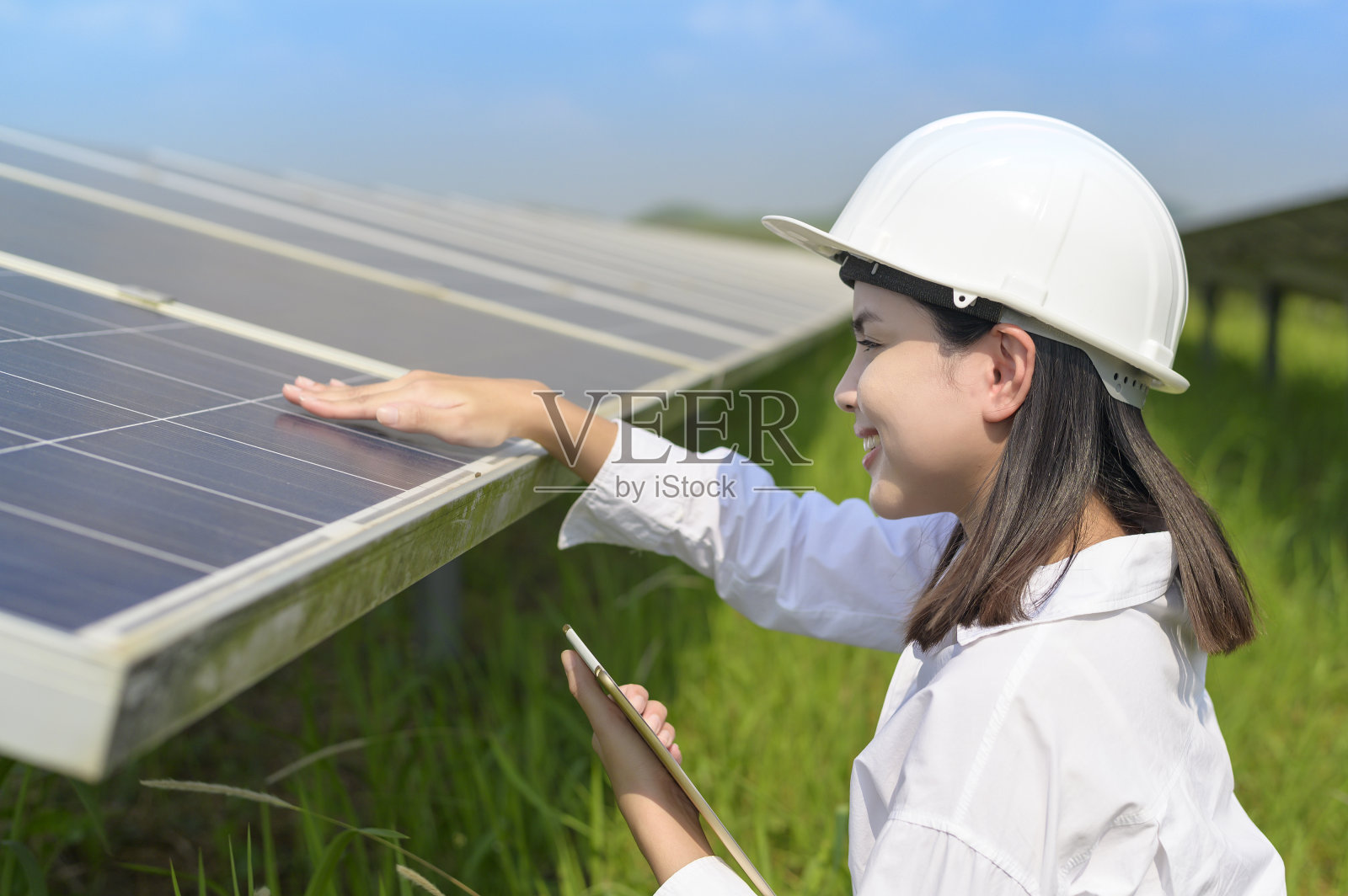 戴着头盔的女工程师在光伏电池场或太阳能电池板场，环保和清洁能源。照片摄影图片