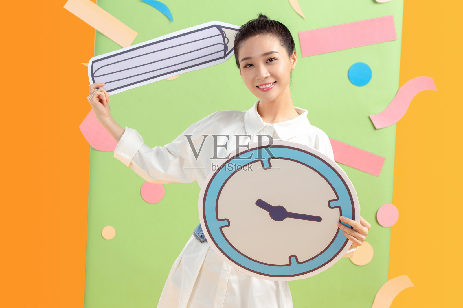 拿着闹钟铅笔的年轻女孩照片摄影图片