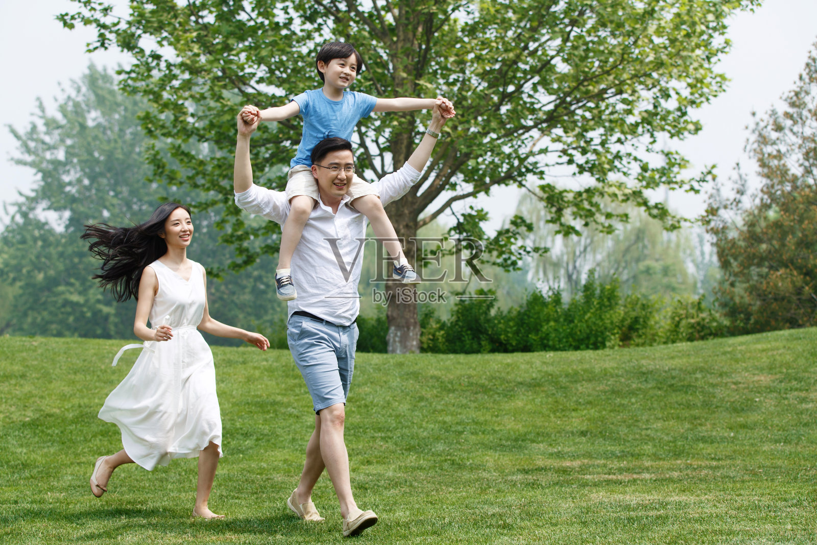 一家三口在草地上奔跑照片摄影图片