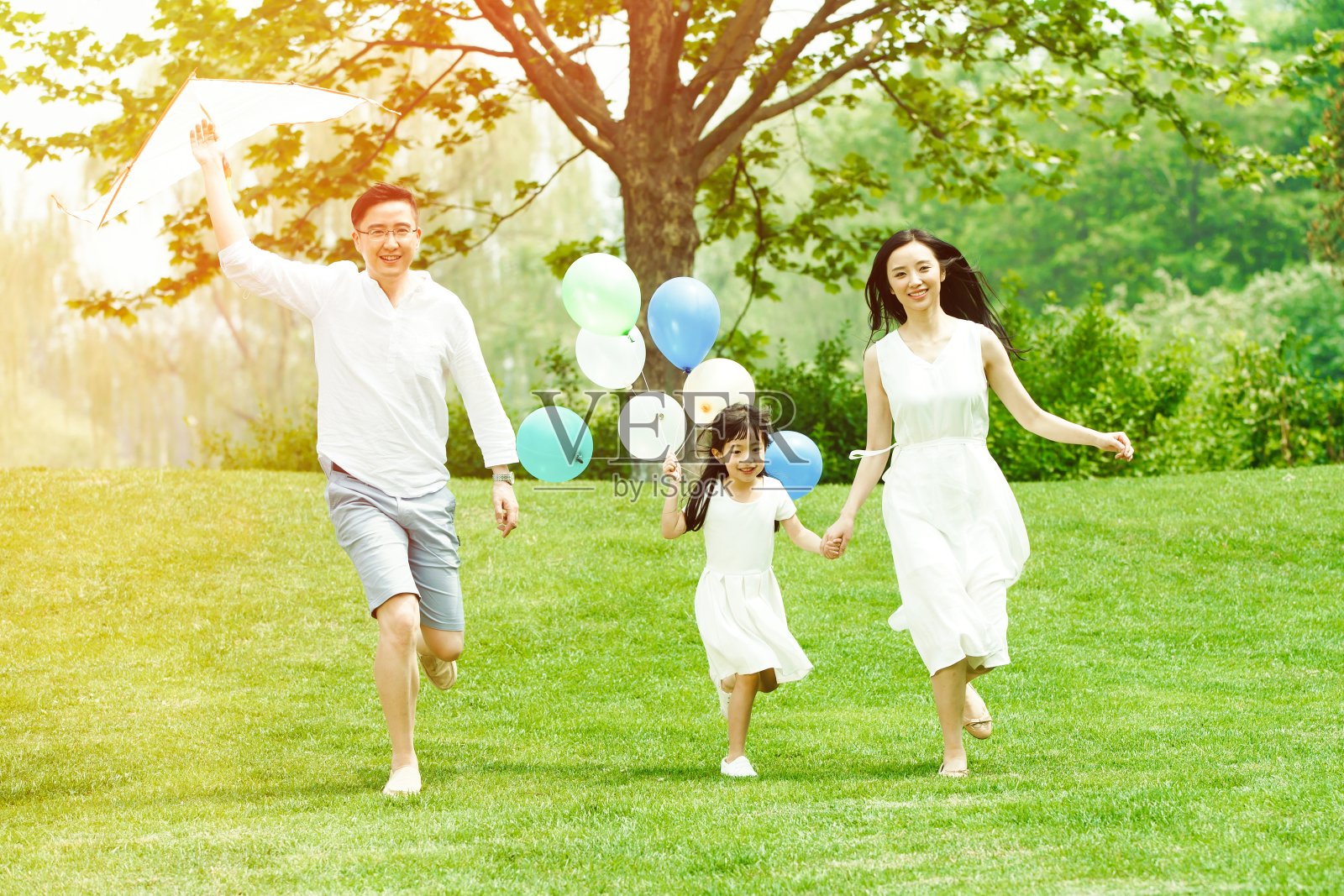 一家三口在草地上奔跑照片摄影图片