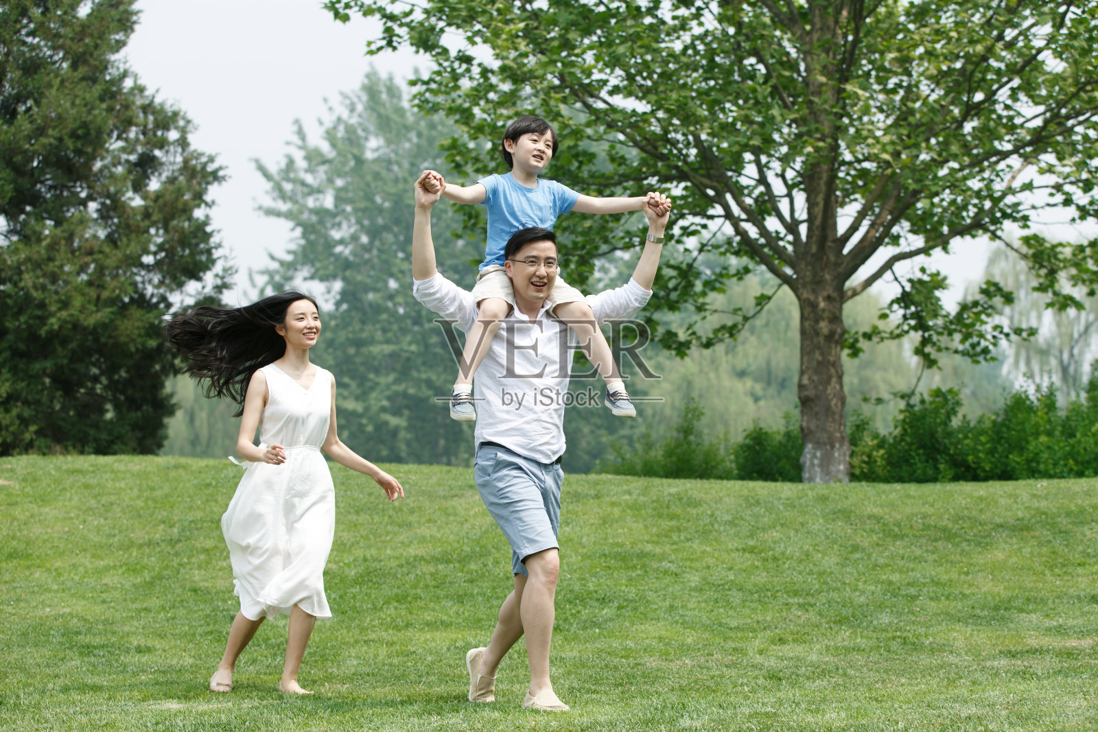 一家三口在草地上玩耍照片摄影图片