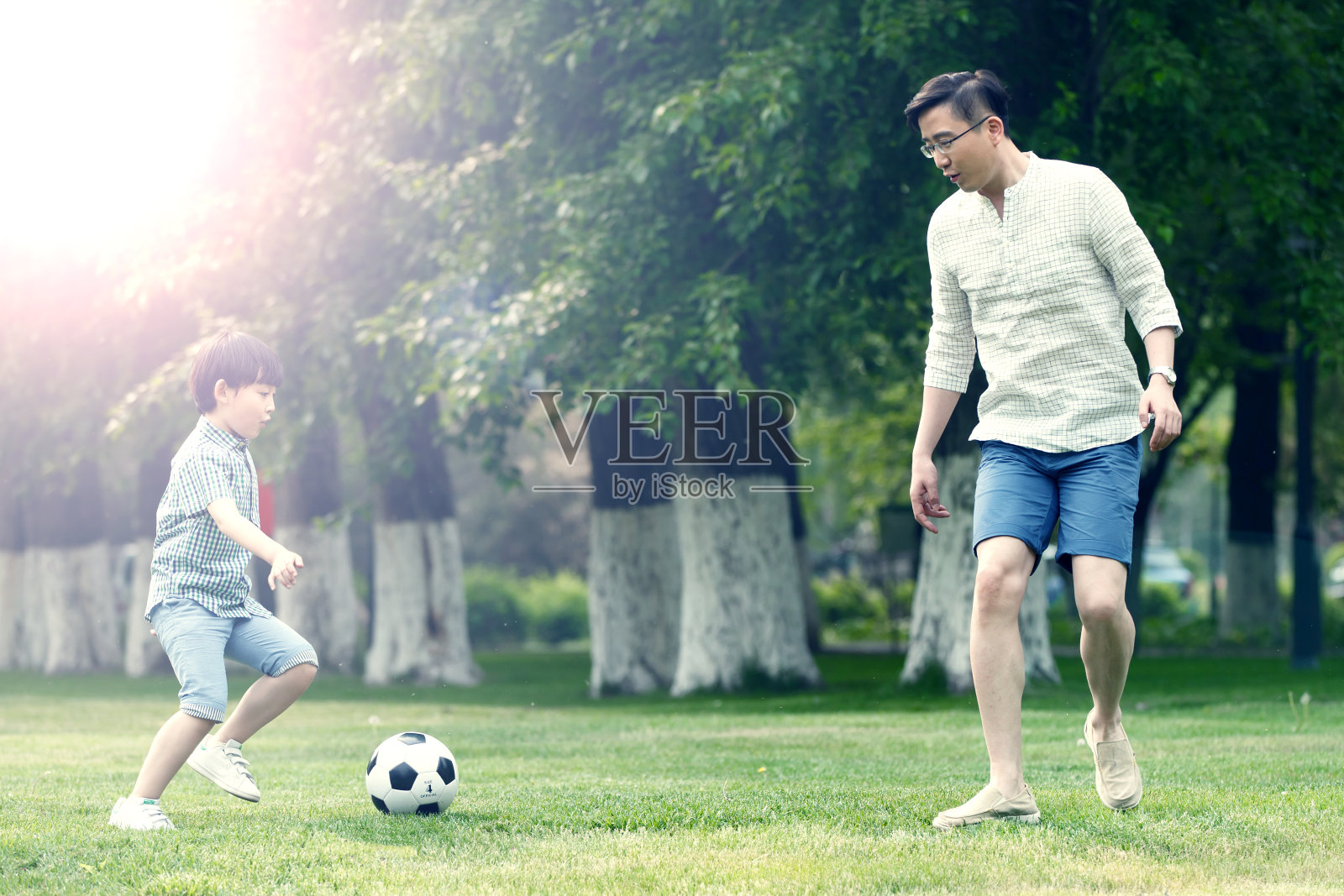 快乐父子在草地上踢足球照片摄影图片