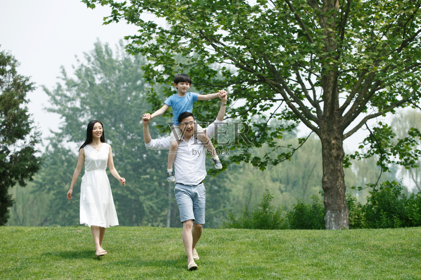 一家三口在草地上玩耍照片摄影图片