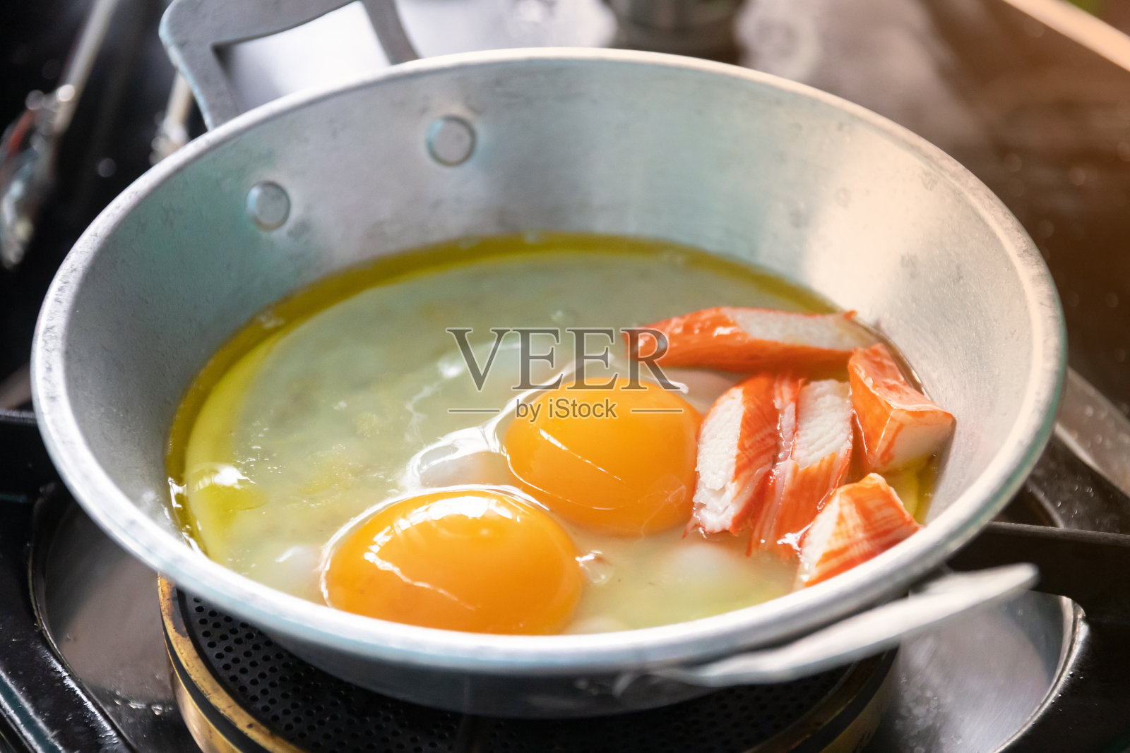 鸡蛋在一个小平底锅里煮，上面撒上甜香肠和猪肉条。平底煎蛋或“Kai Grata”是一种在泰国很受欢迎的早餐。照片摄影图片