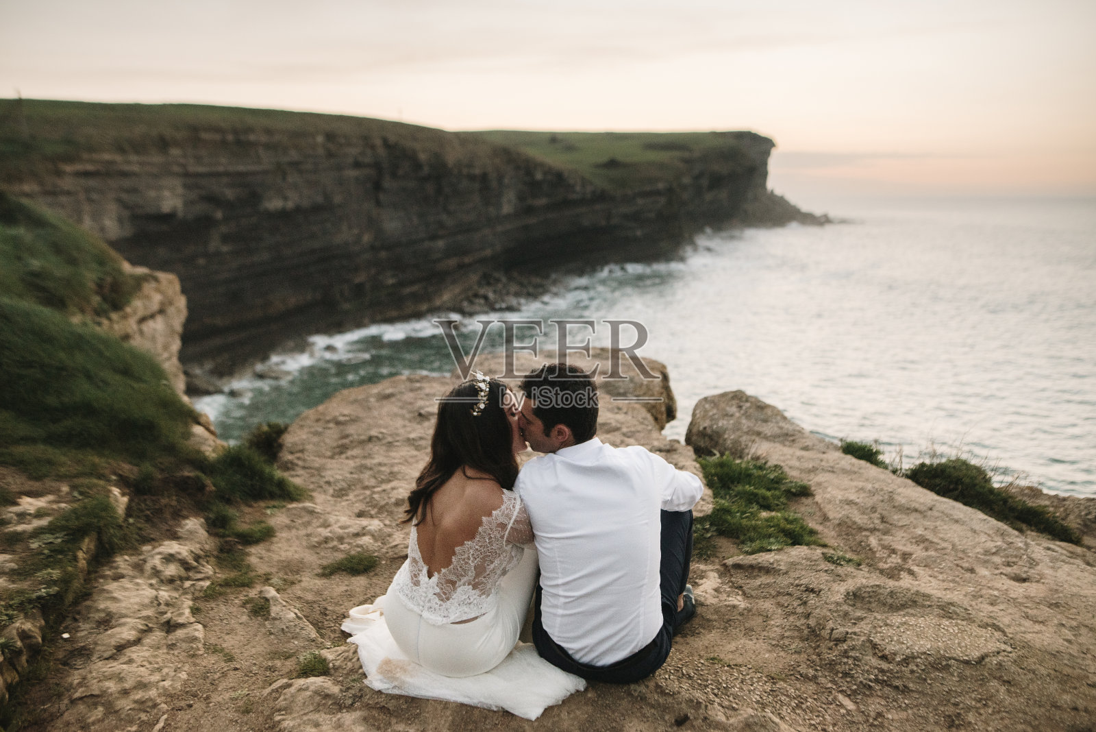 一对新婚夫妇坐在海边看日落照片摄影图片