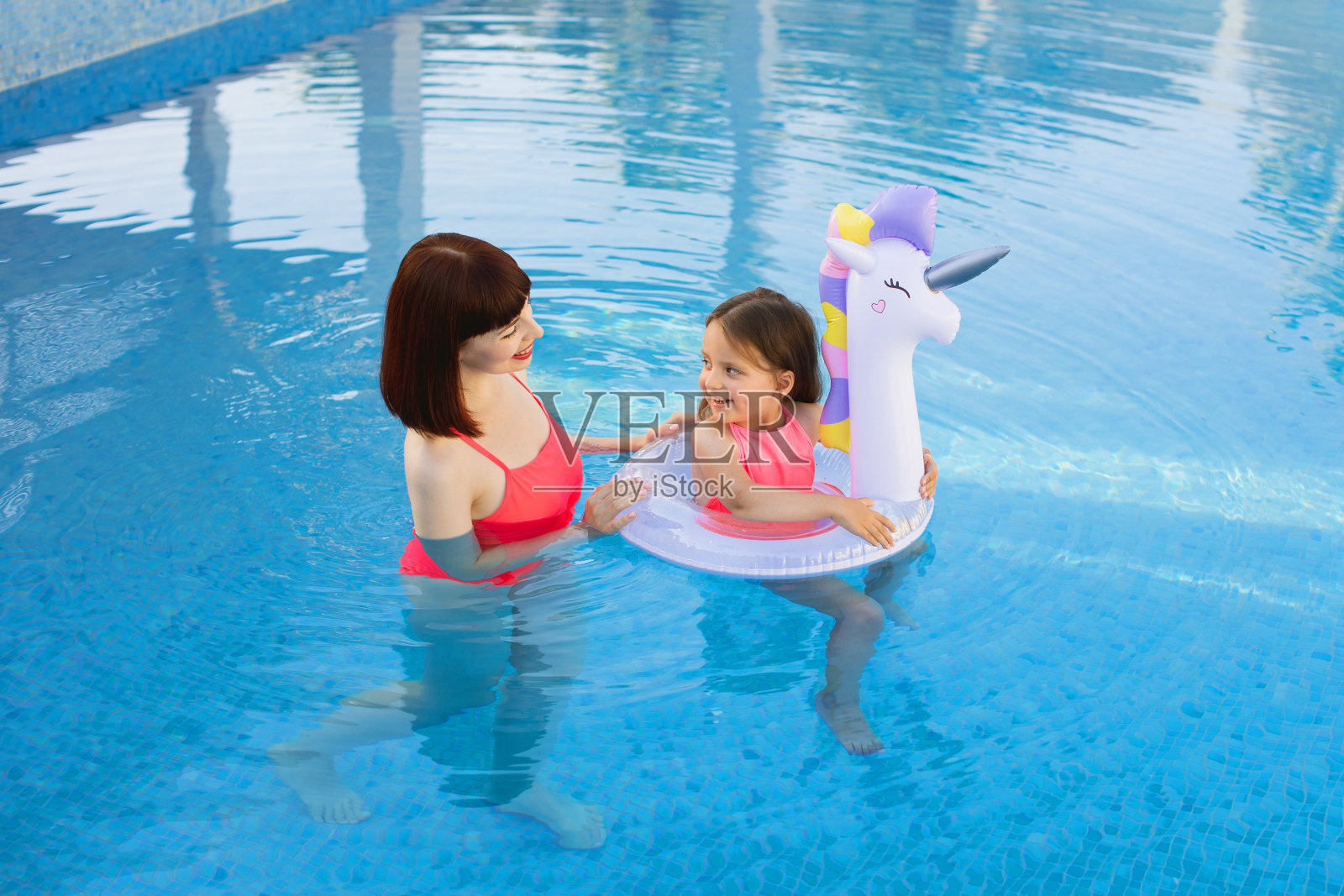 快乐的母女在休闲中心的泳池里。照片摄影图片