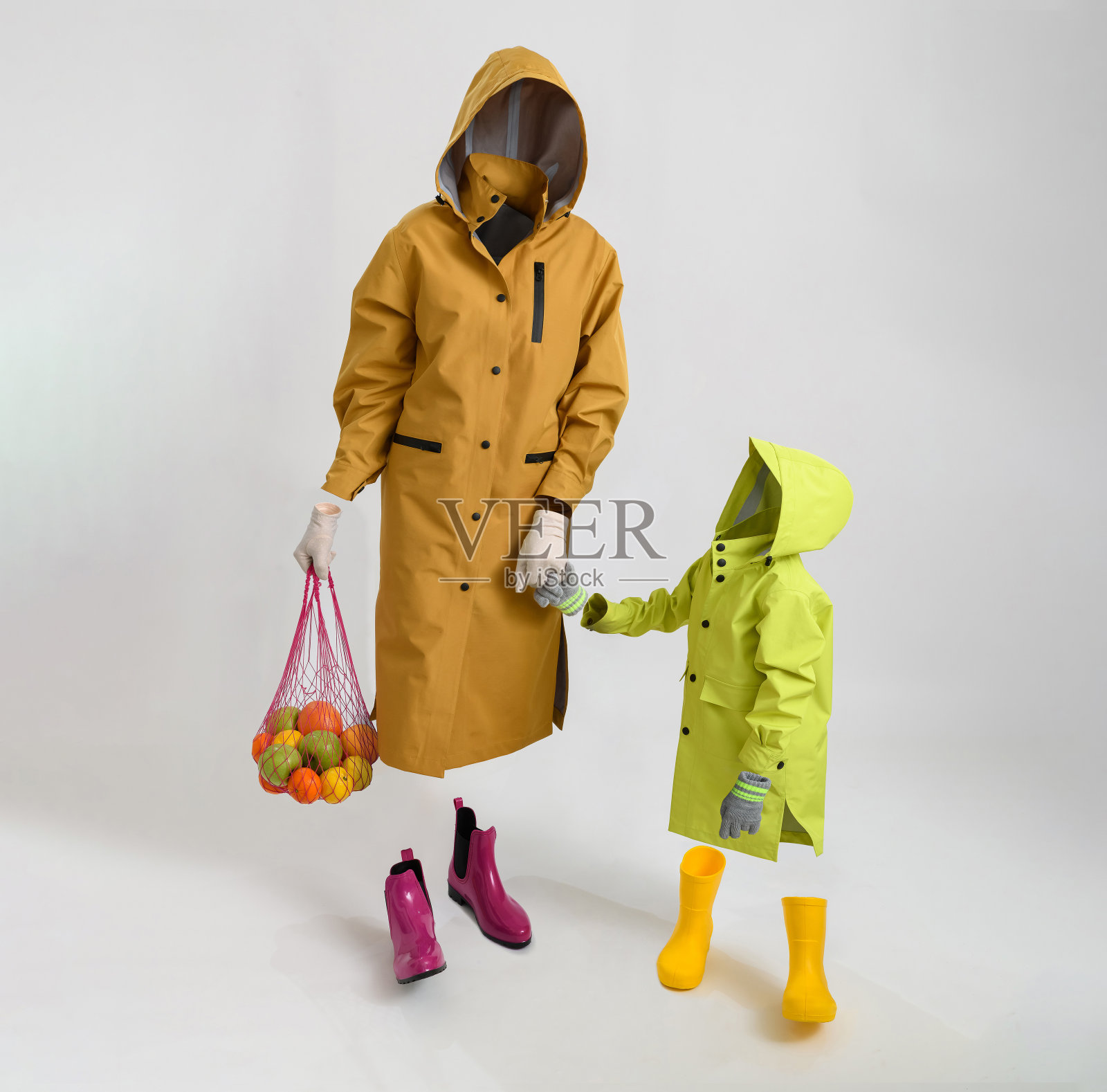 隐形人体模型上的衣服。妈妈和儿子穿着雨衣和胶靴。观念摄影照片摄影图片