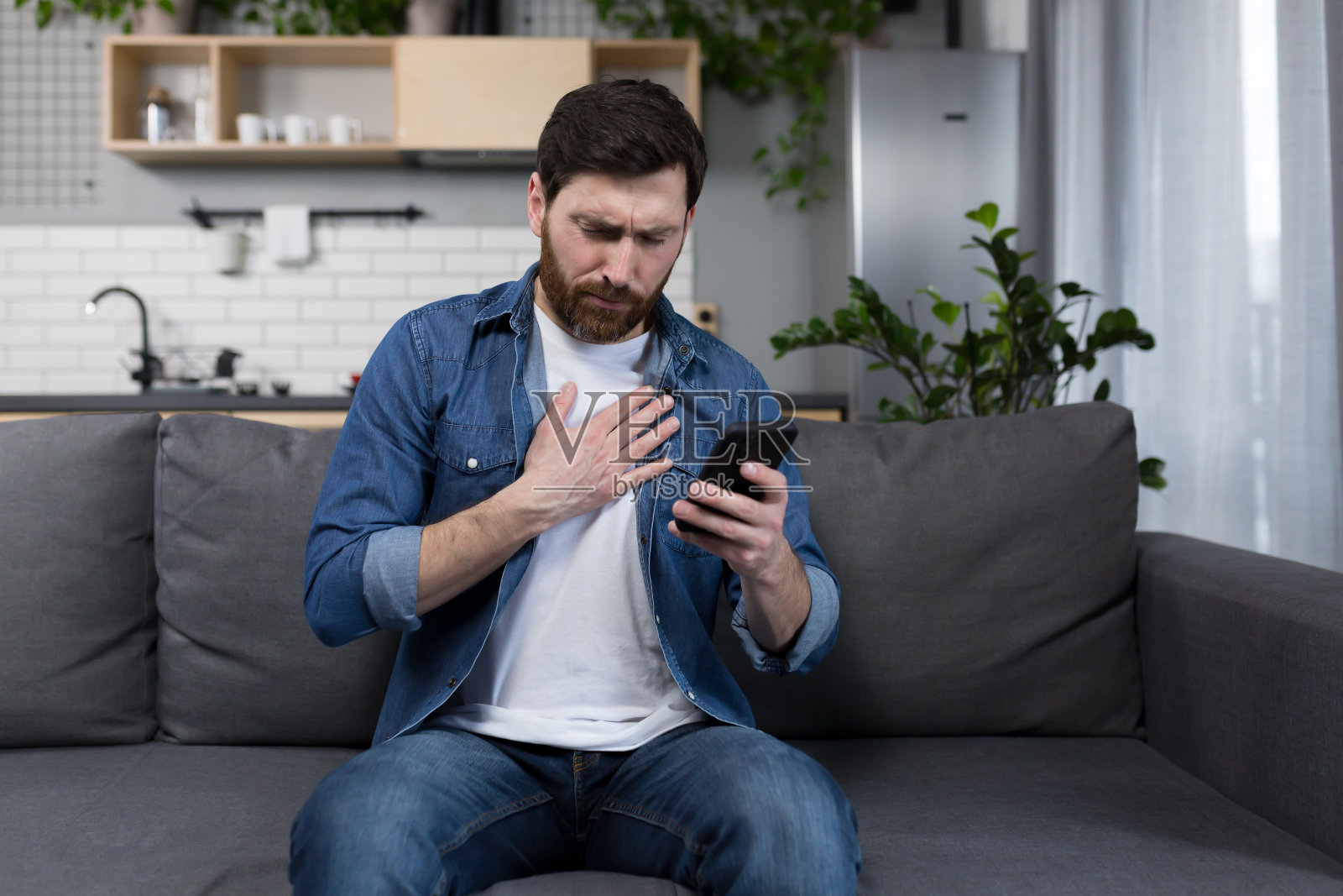 病人在家，突然心痛，坐在沙发上，双手捂着胸口照片摄影图片