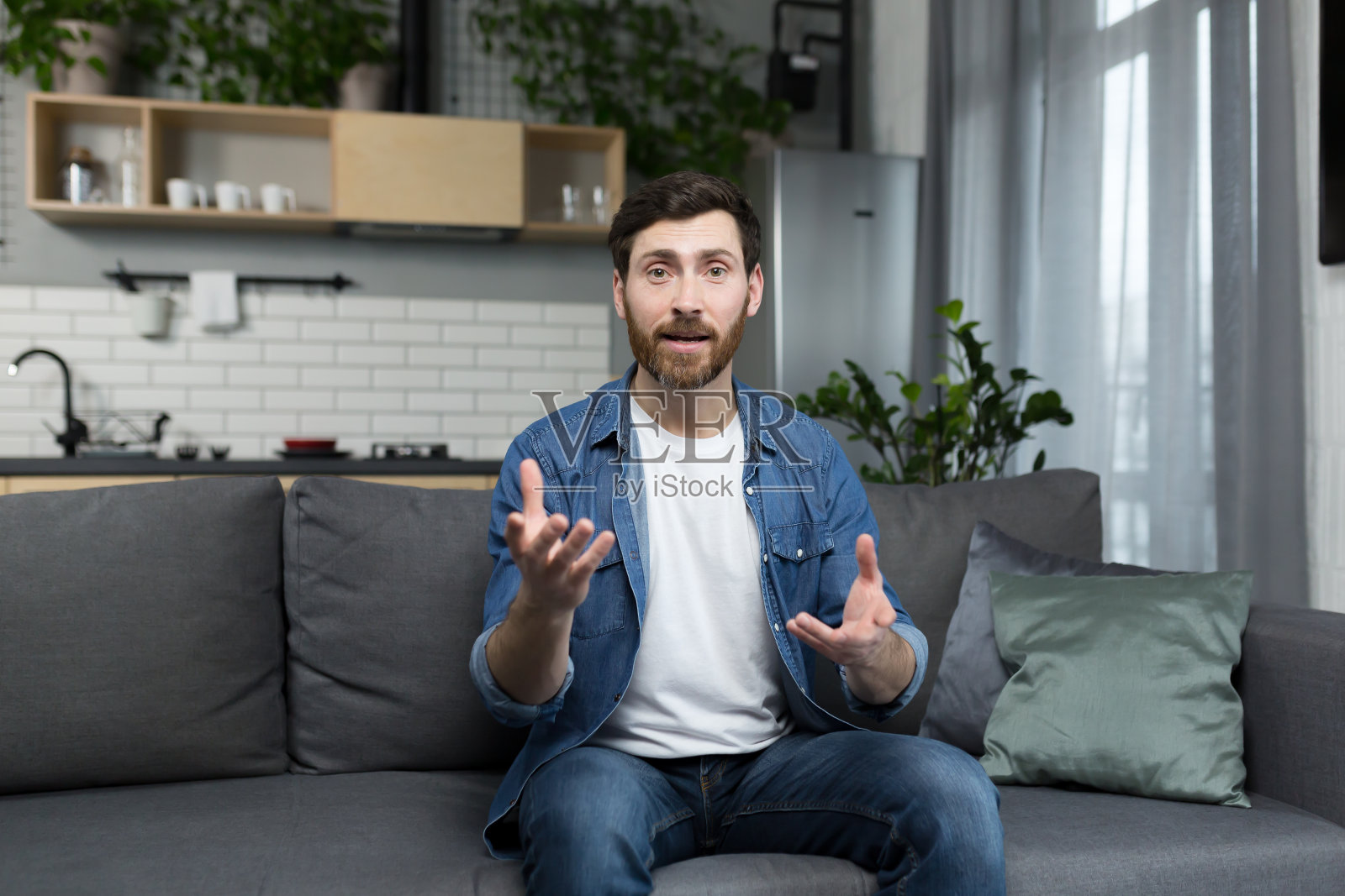 一名男子坐在家里的沙发上，全神贯注地看着网络摄像头和视频通话照片摄影图片