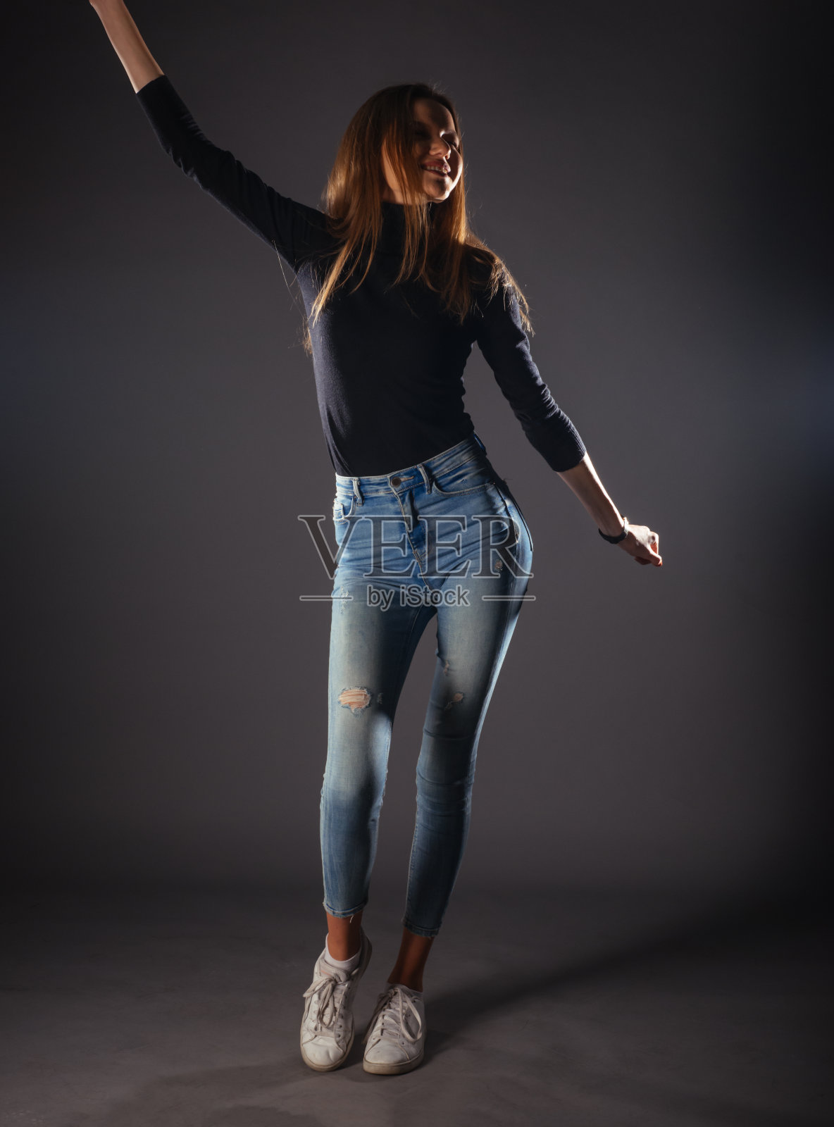 迷人的女模特在牛仔布牛仔裤摆孤立的灰色背景。照片摄影图片