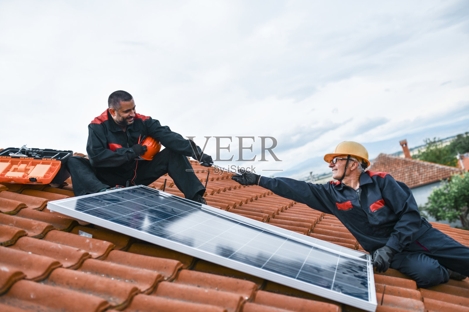 在安装太阳能电池板的过程中，老员工和年轻员工展示了他们的工艺和团队合作精神照片摄影图片