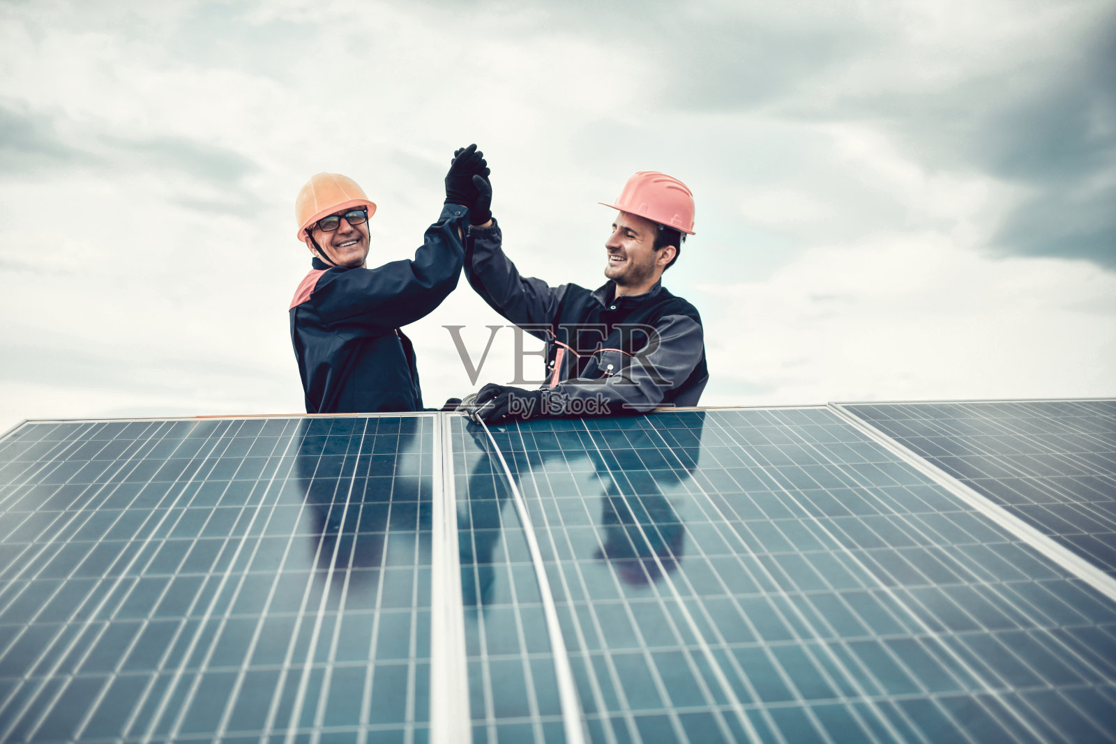 两个不同年龄的男工人击掌成功安装屋顶光伏板照片摄影图片